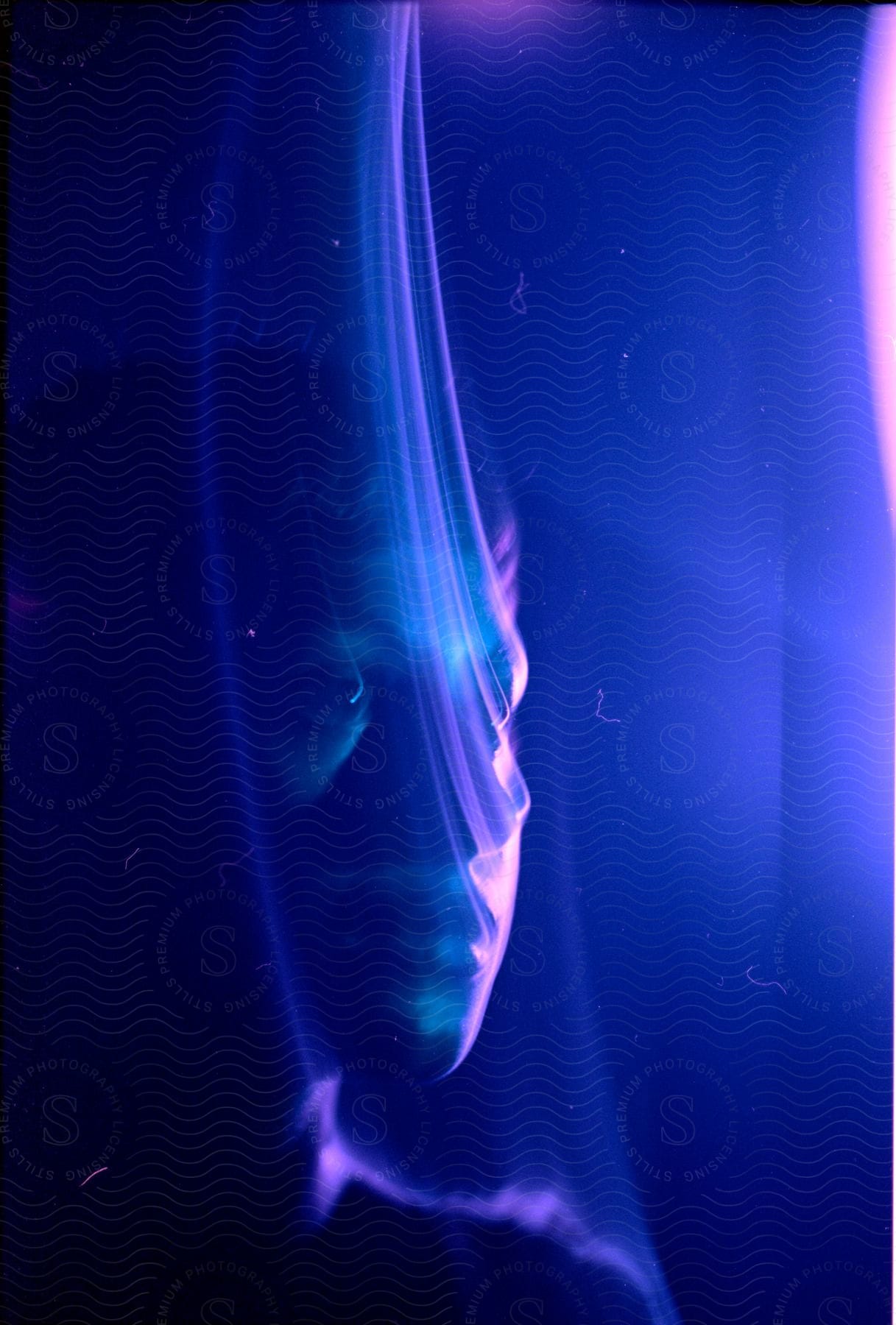 Close up of a young mans face with color trails under blue lights