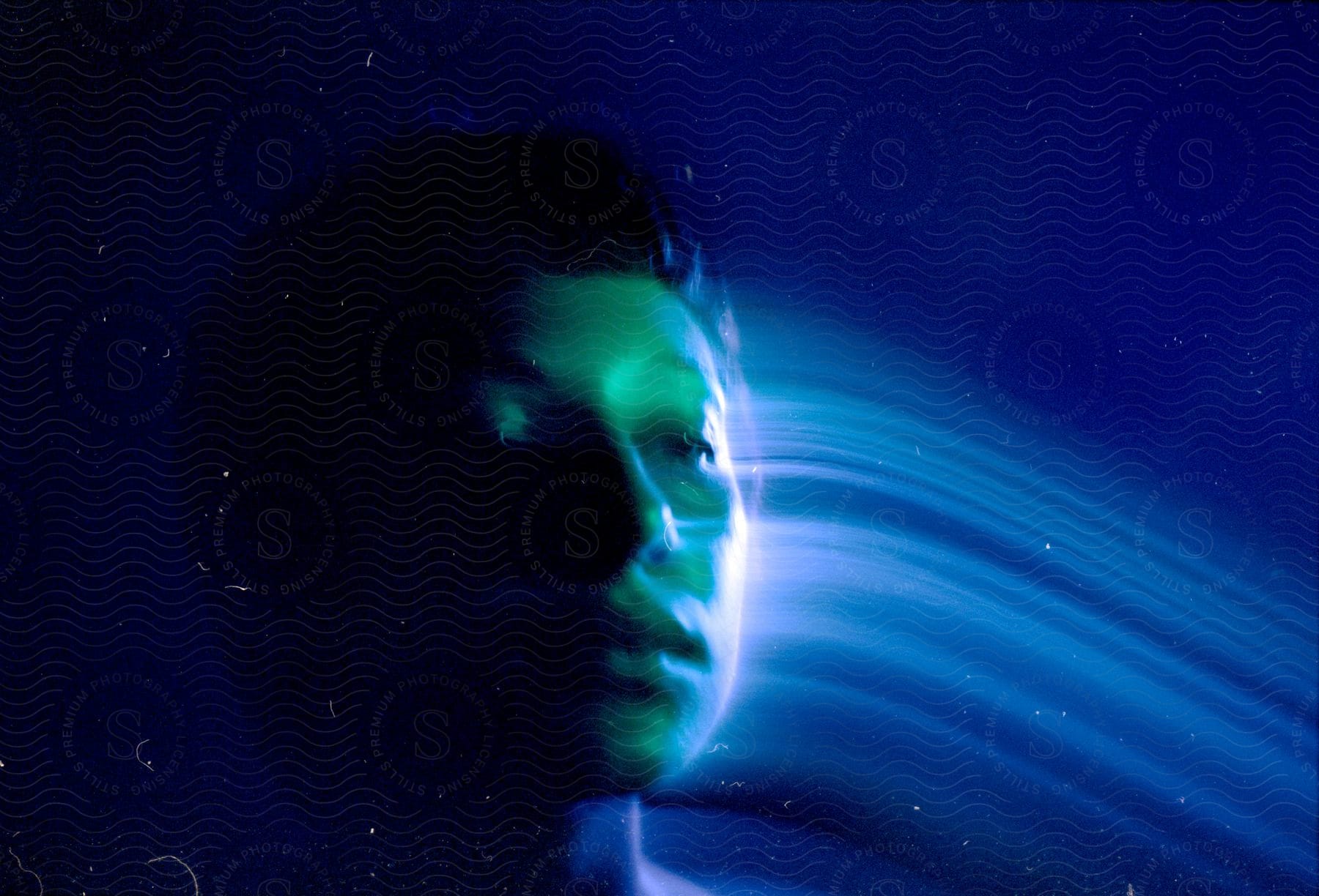 Young man leaving a trail of light on a blue background