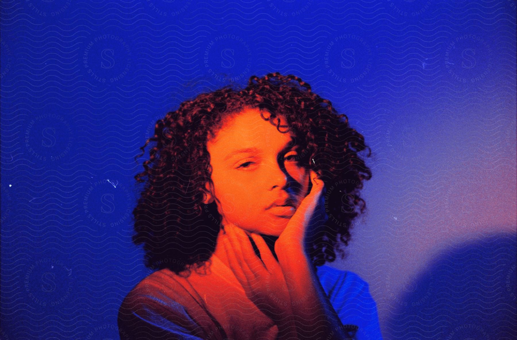 Young woman posing with her hands on her face against a blue background