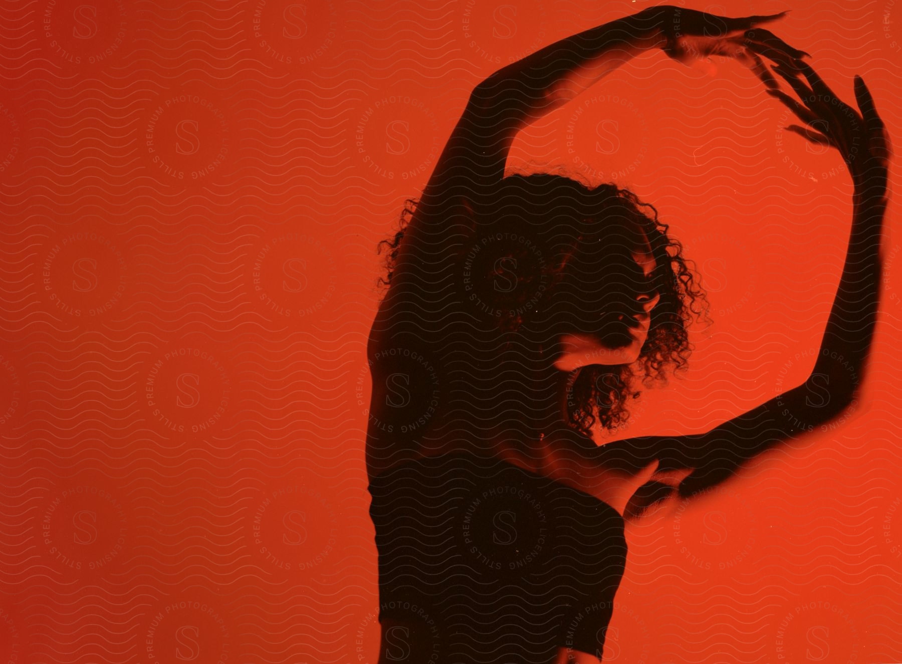 A woman dancing with a happy expression backlit against a sky and water backdrop