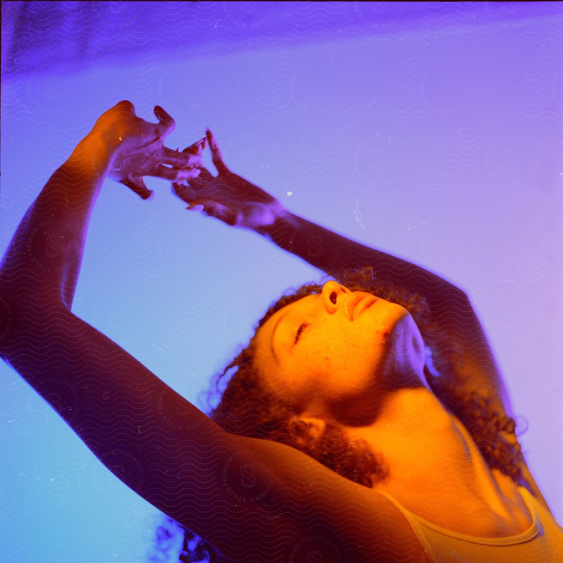 A young woman posing with her hands up.