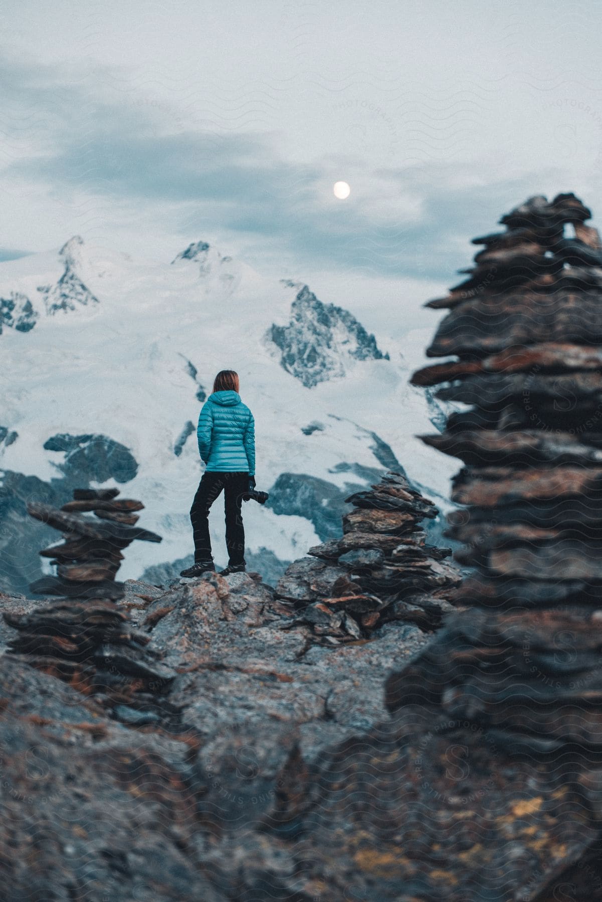 A woman stands outdoors in the mountains