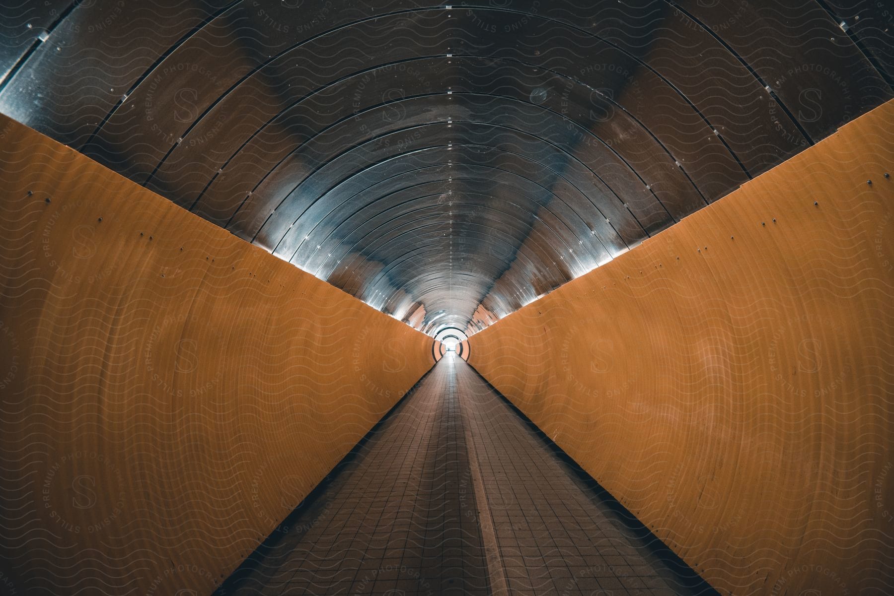 A long tunnel with a round metal ceiling and painted yellow culvert walls