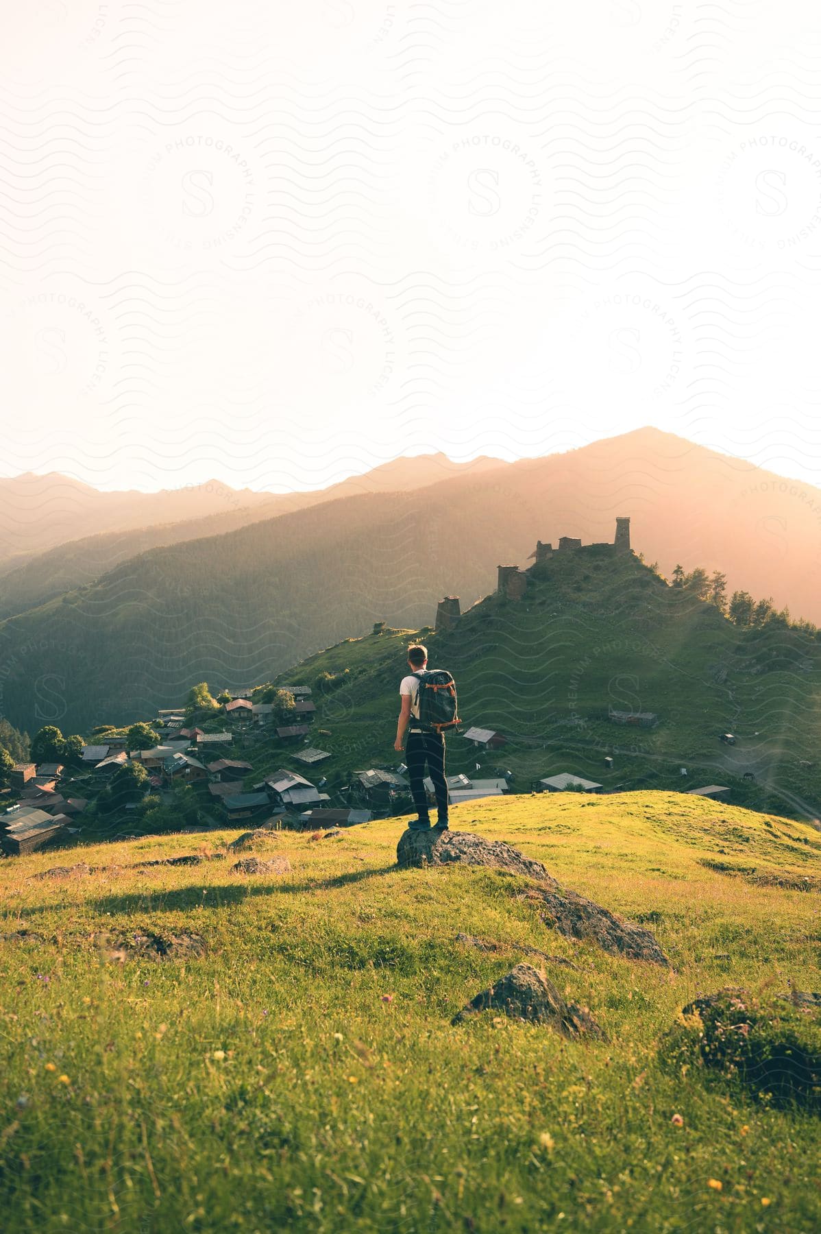 Backpacker standing on hillside overlooking rural town in georgia