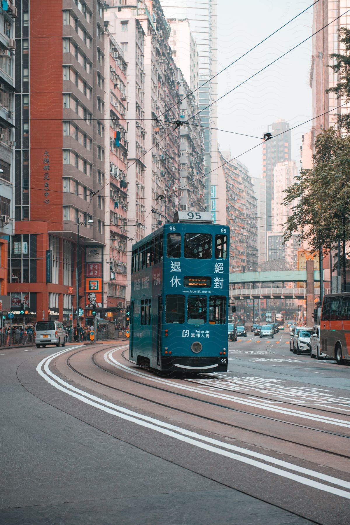 A blue double decker bus drives through downtown in a large japanese city