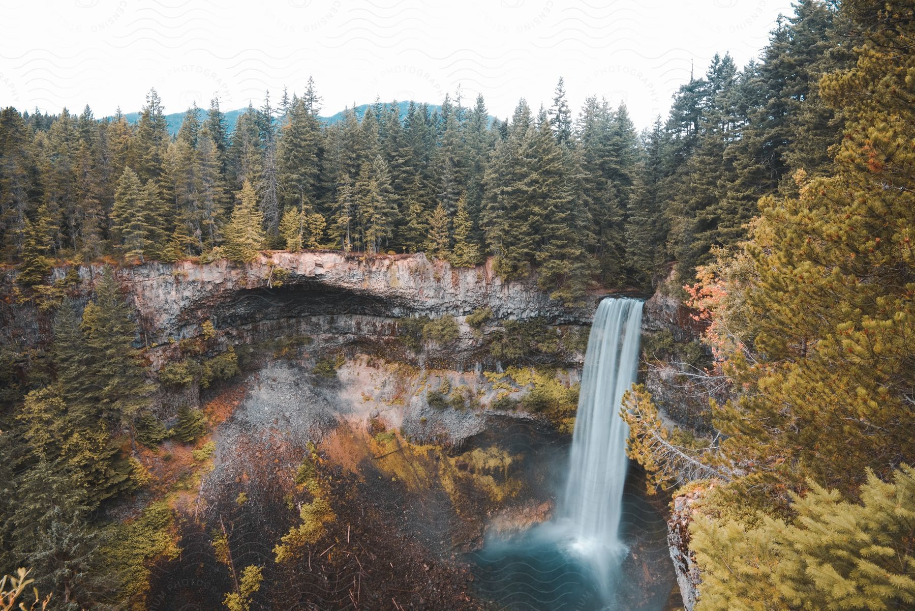 Aerial perspective of a waterfall surrounded by trees in a wooded landscape