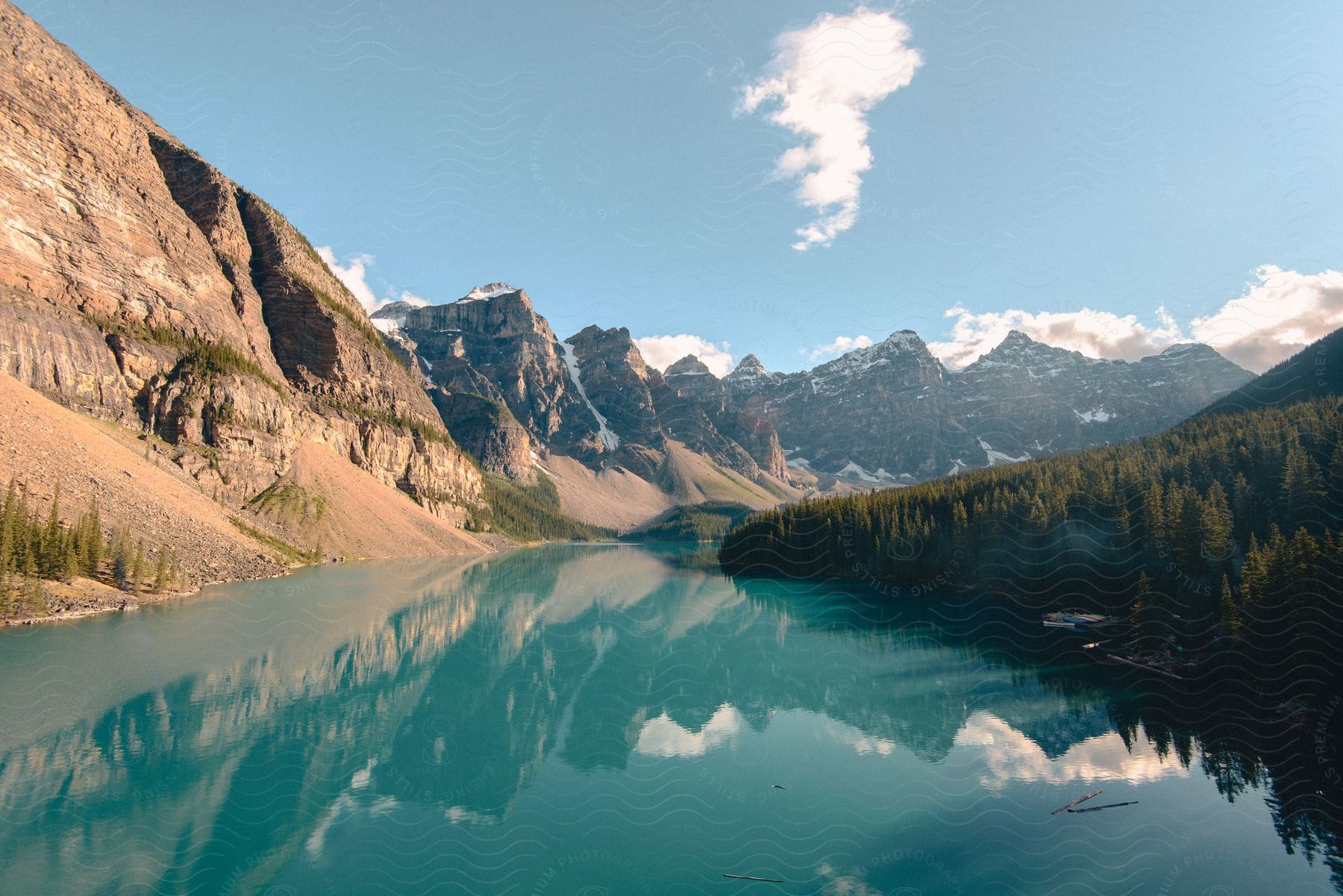 A still lake surrounded by forest and steep snowcovered cliff sides on a cloudy day in canada