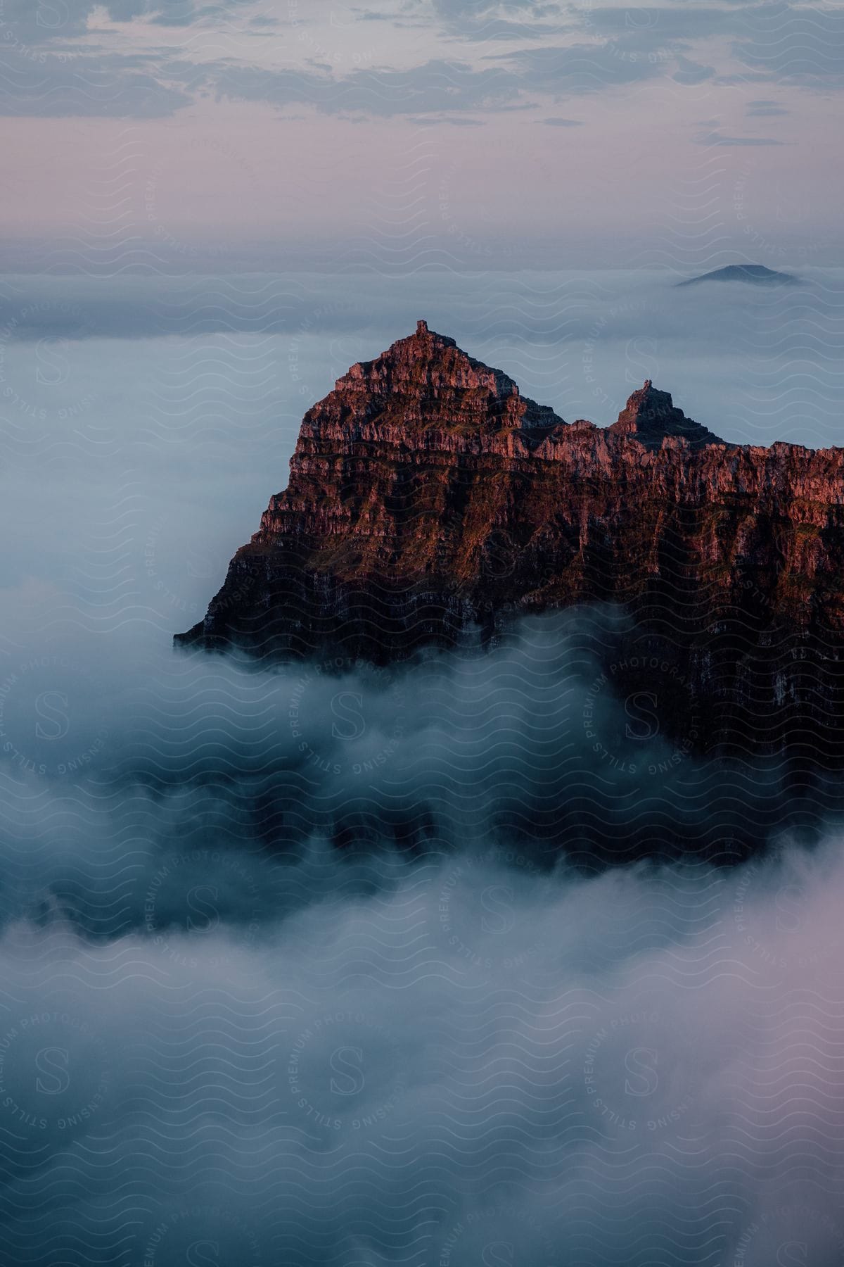 Rocky mountain tops visible above clouds during sunset