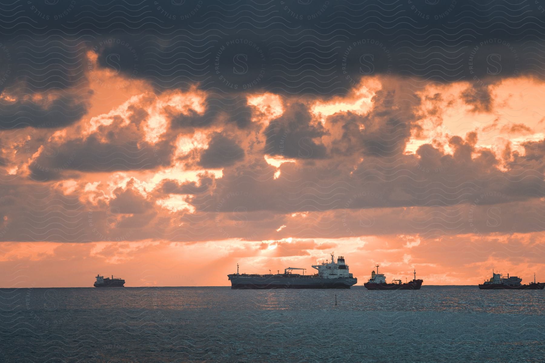 Cargo ships in the ocean at sunrise on a cloudy day