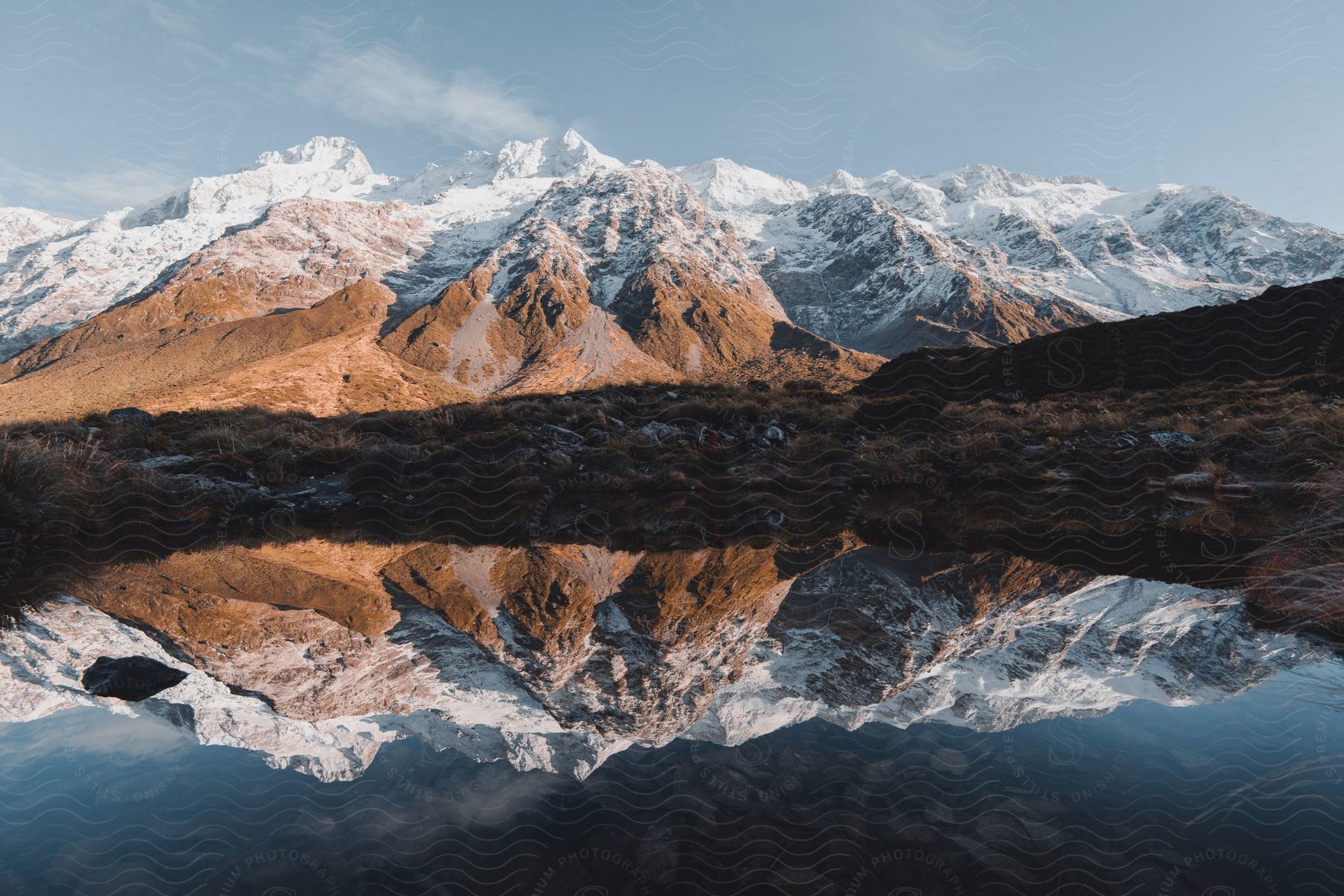 Mirror image of snowcapped peaks on a serene lake in new zealand