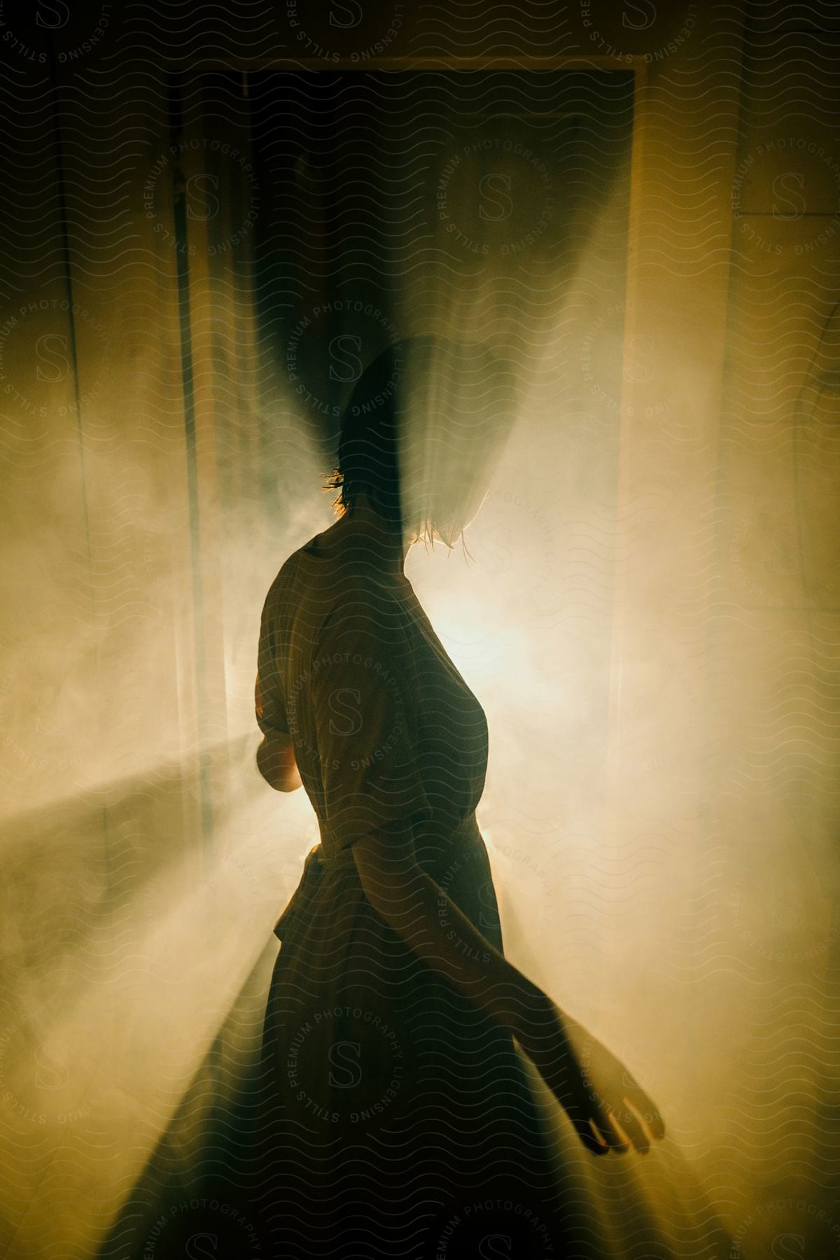 Woman standing in a dark room facing a door with strong light coming through