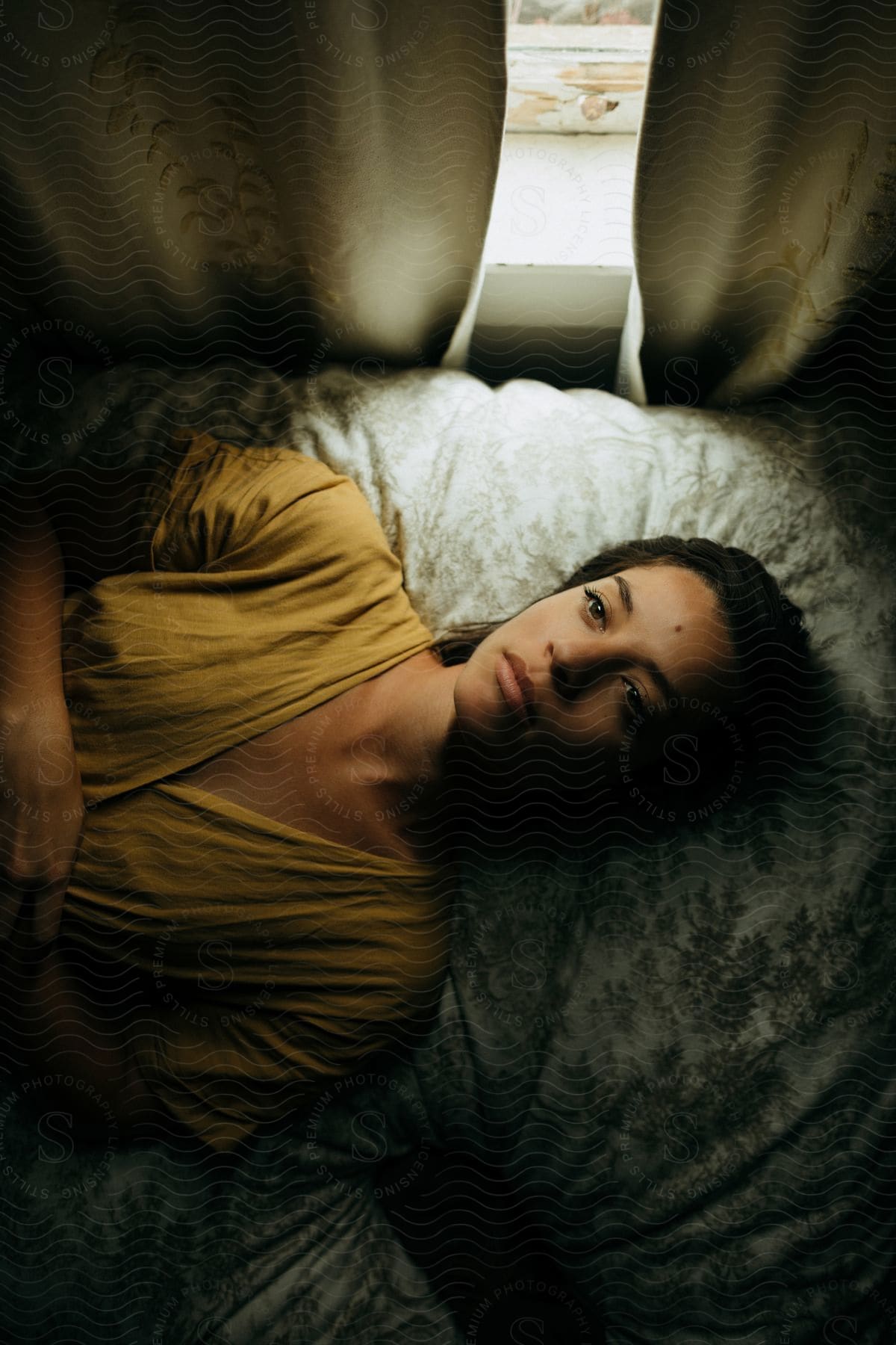 A woman lying on her bed looking up at the ceiling