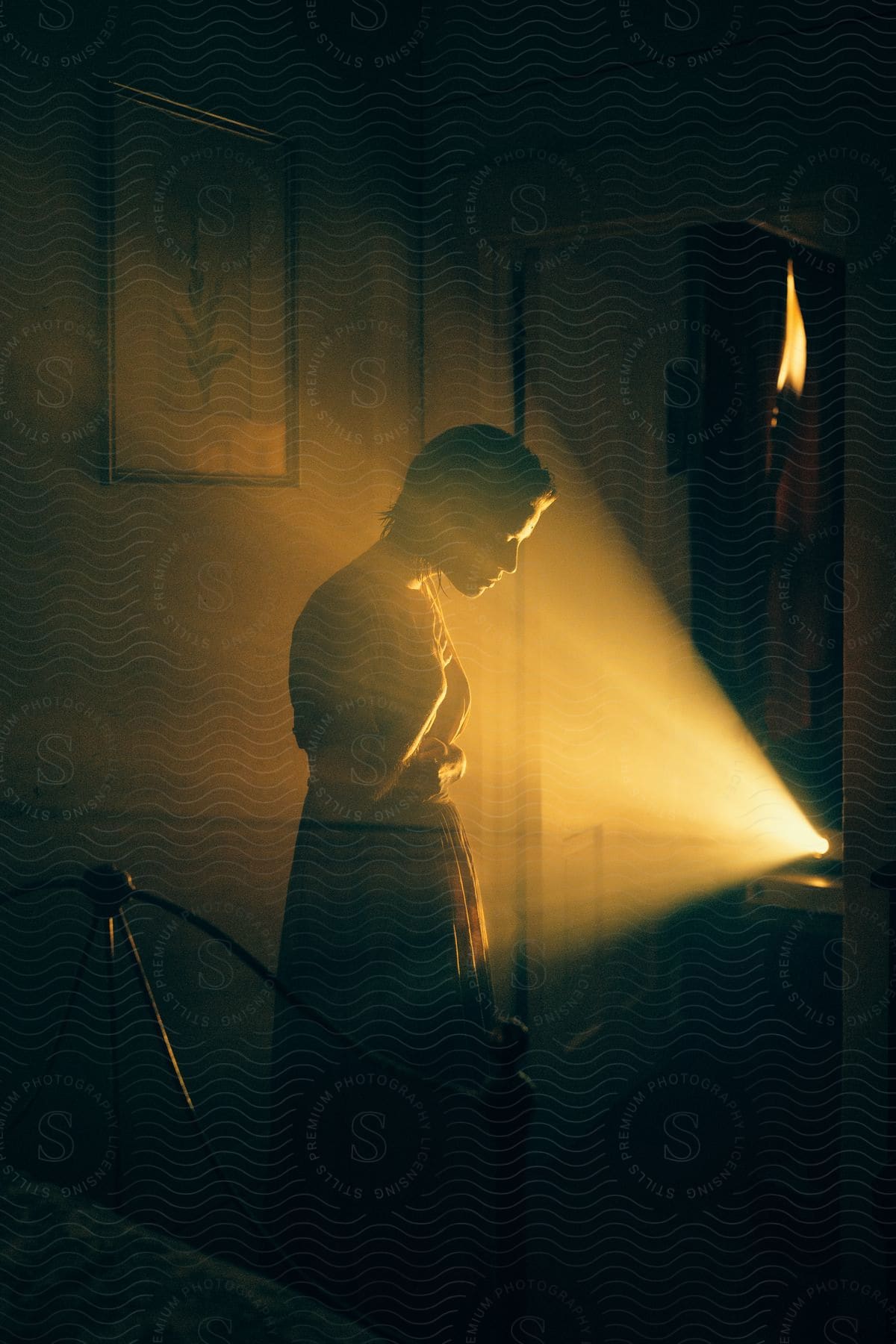 Woman standing in a bedroom next to a projector light with hands against her chest