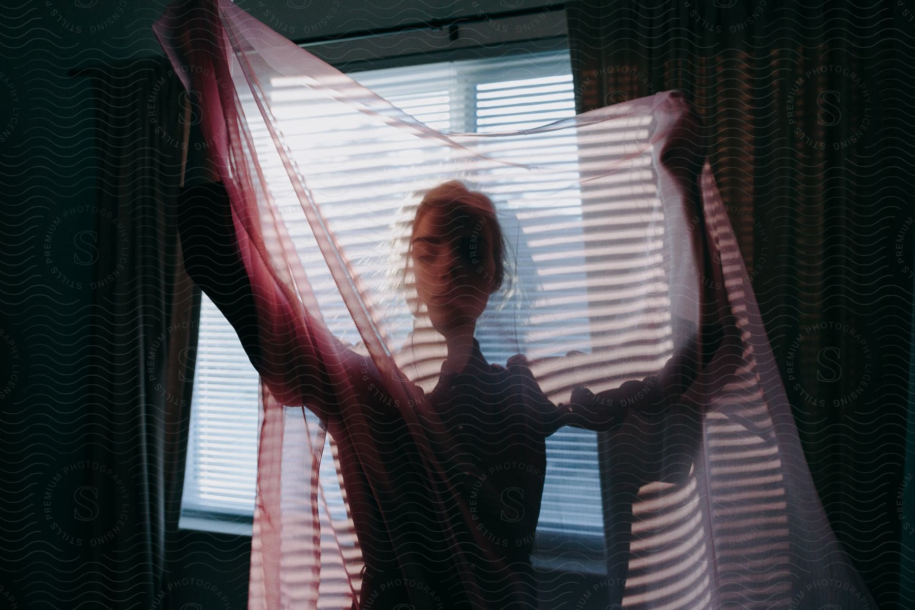 Woman holding a veil next to a window light patterns projected into the room