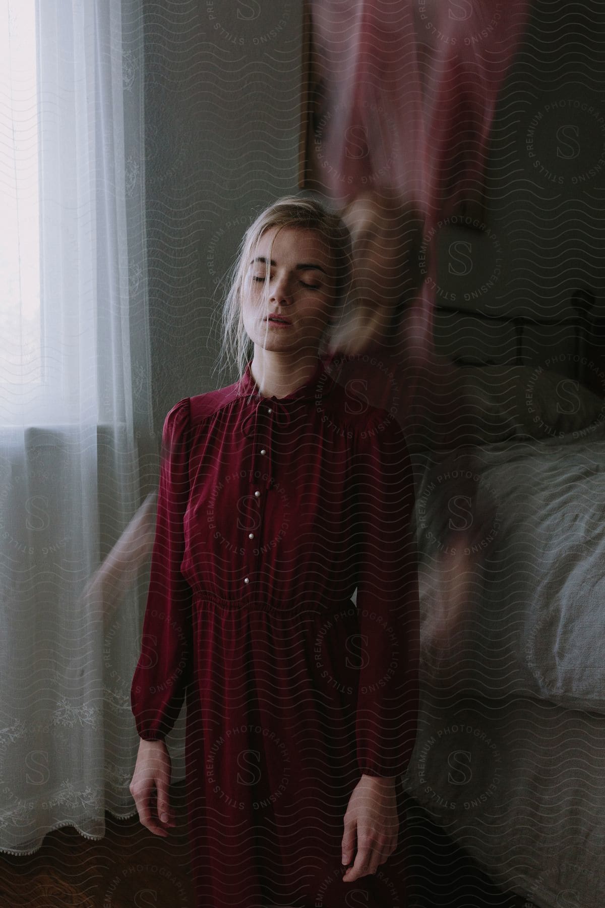 Blonde woman dressed in red kneeling on the floor in a double exposure image