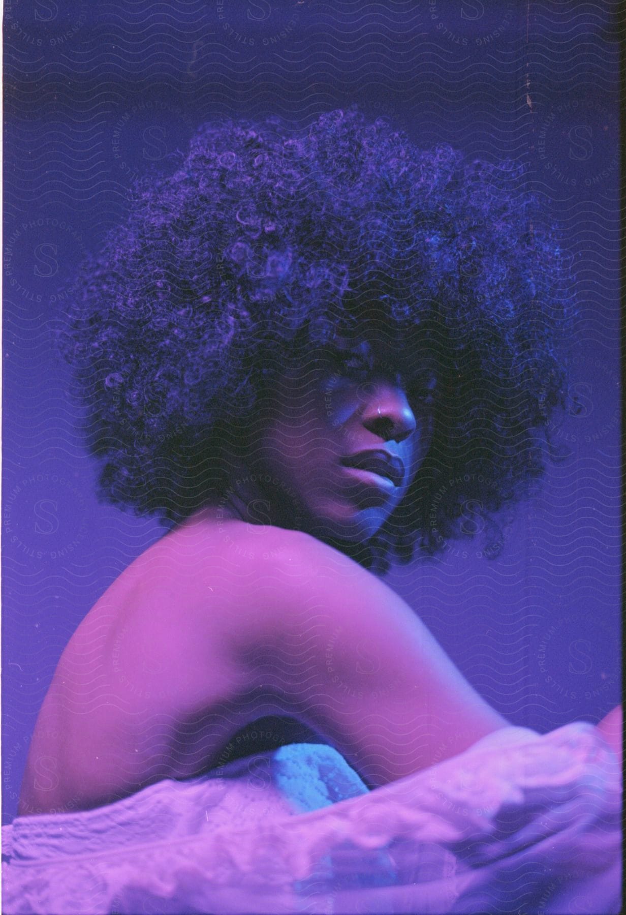 A black woman with an afro hairstyle under blue and pink lights