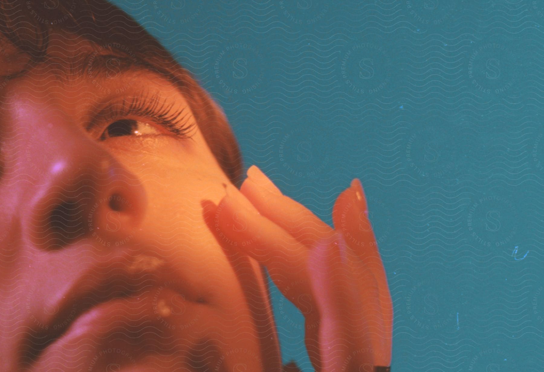 Close up of womans hand touching her cheek and looking up in a studio