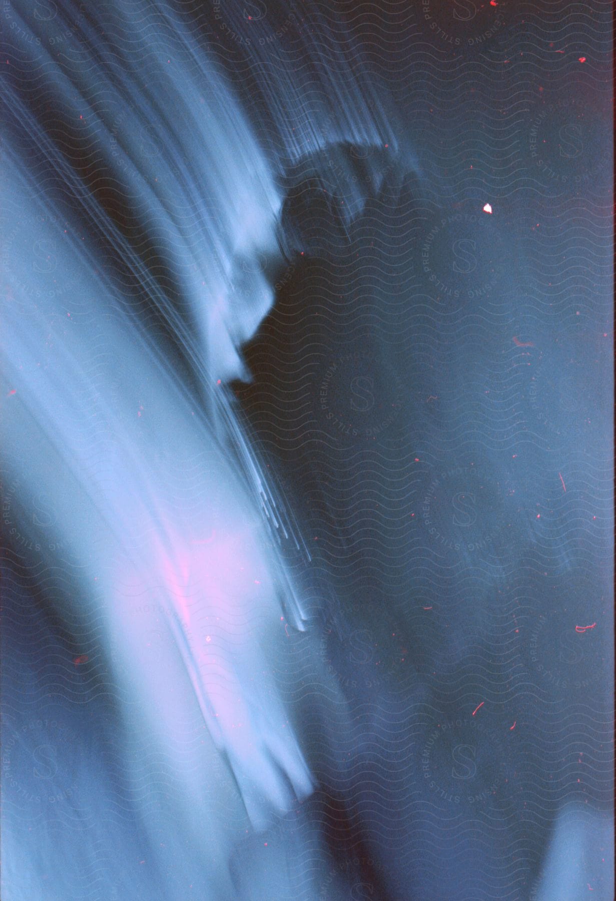 Close up of a young womans face leaving color trails in a dark room