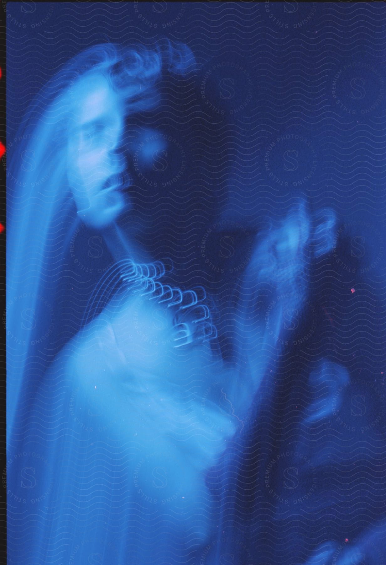 Abstract image of a womans face and body distorted by motion blur under blue lights