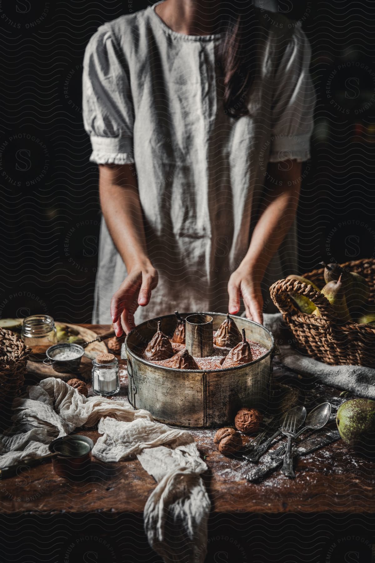 Woman stands at table strewn with pear dessert and the ingredients used