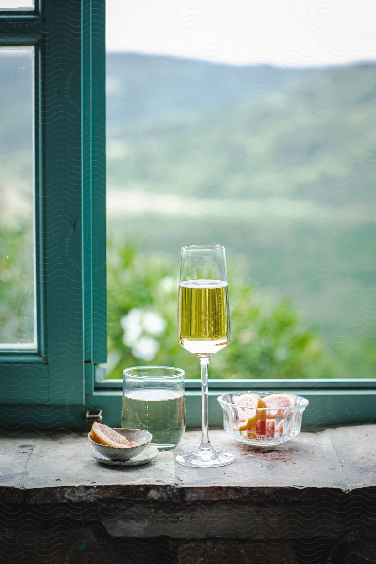 Orange slices and beverage glasses on a window ledge with mountains in the distance