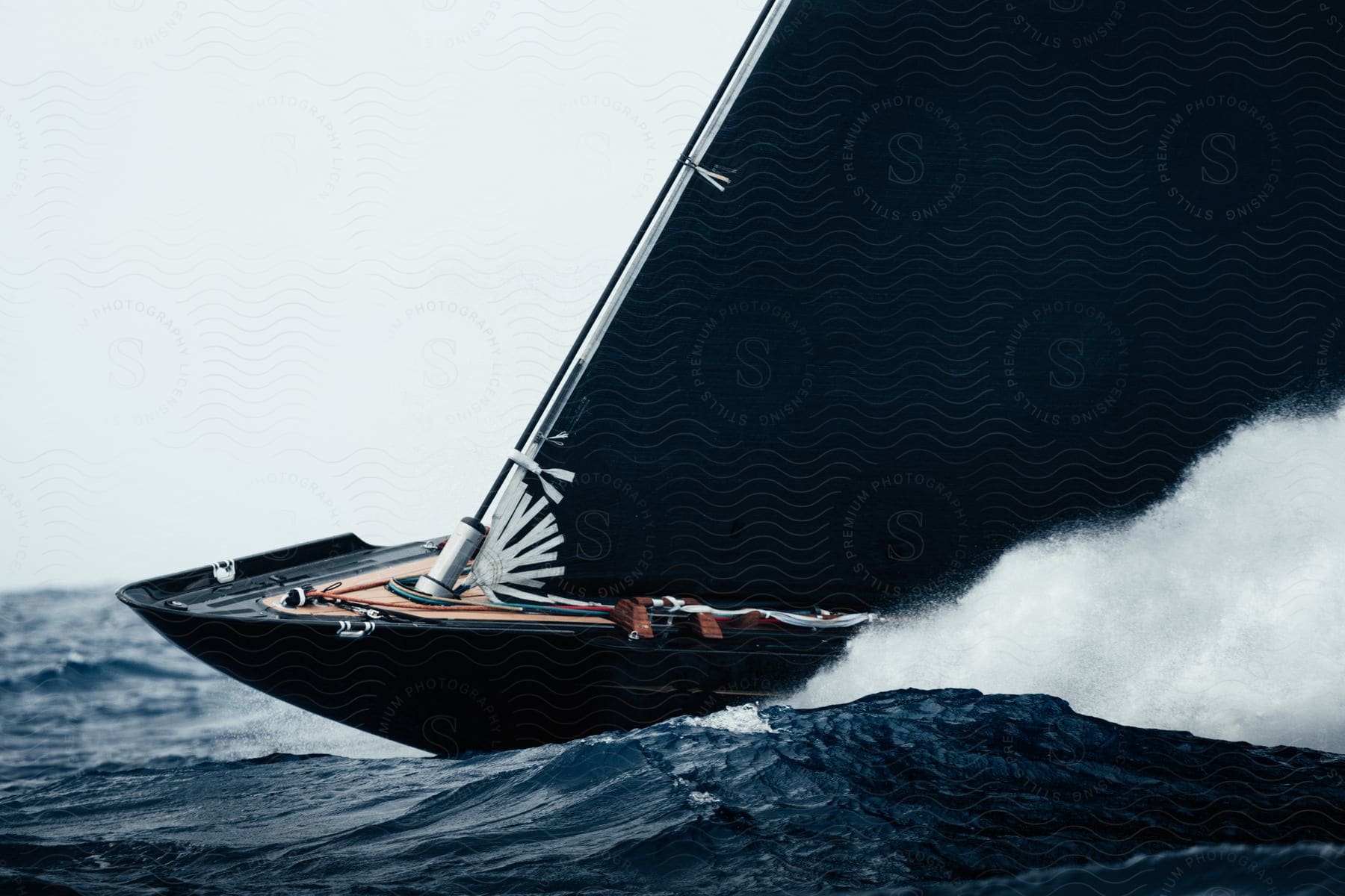 Black sailboat sailing at high speed on the ocean waves