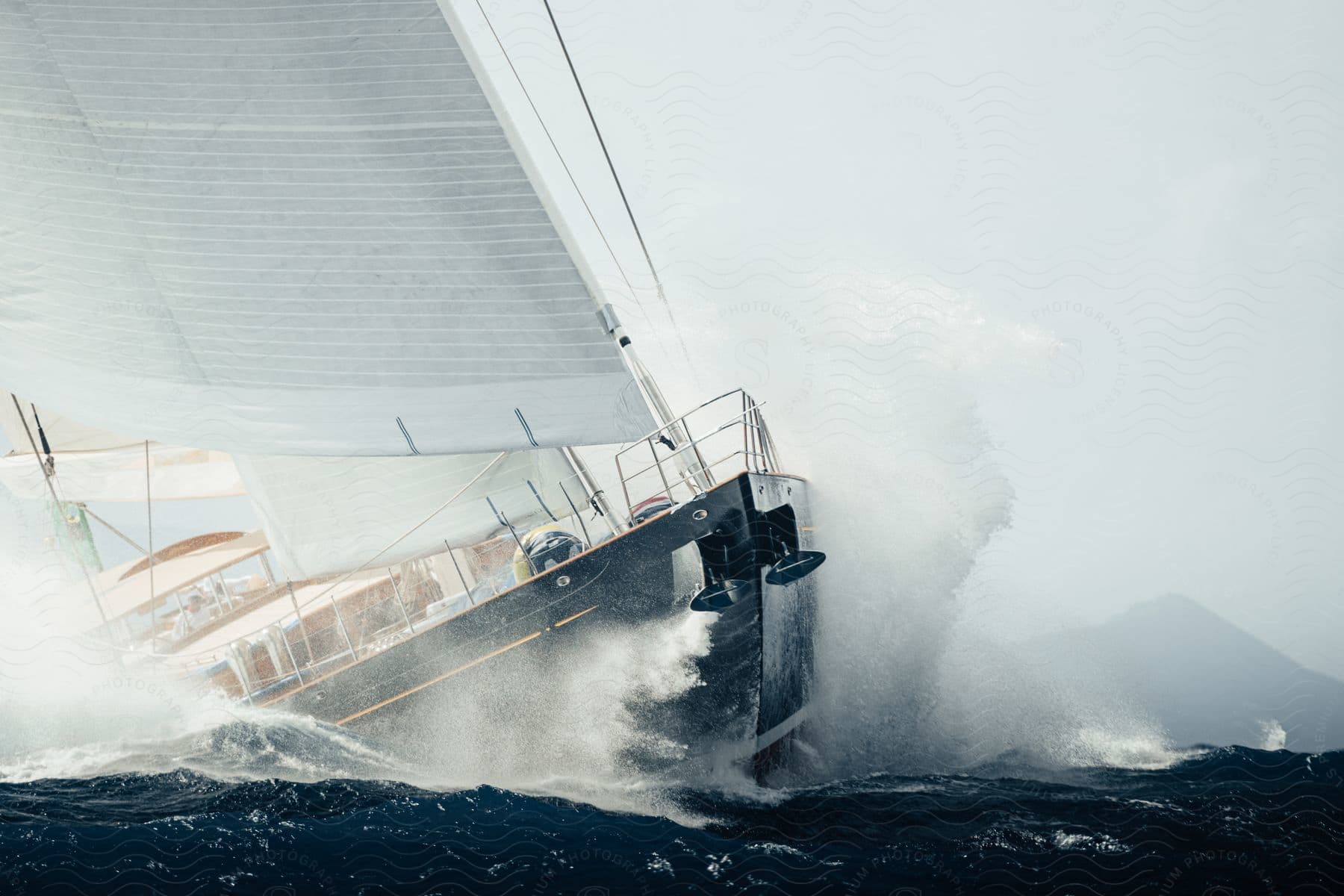 A sailboat is tilted by rough waves while sailing on open water