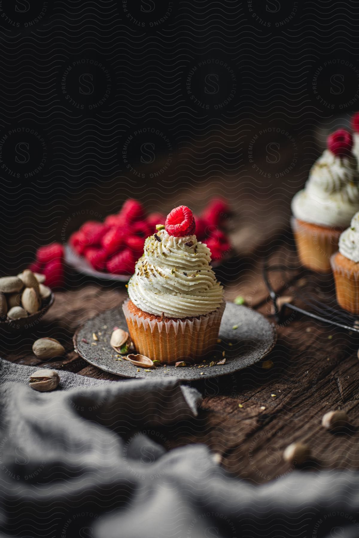 Cupcakes and raspberries on a wooden table with pistachios