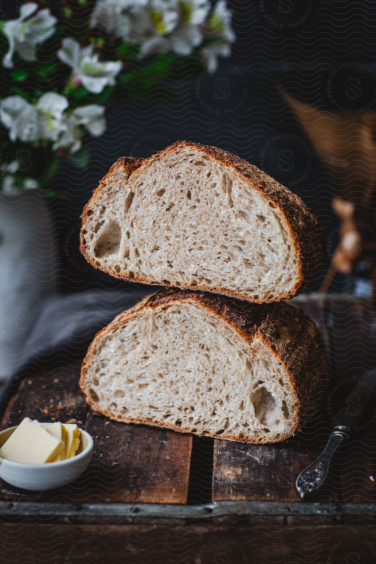 Loaf of sourdough bread cut in half served with butter on a rustic table