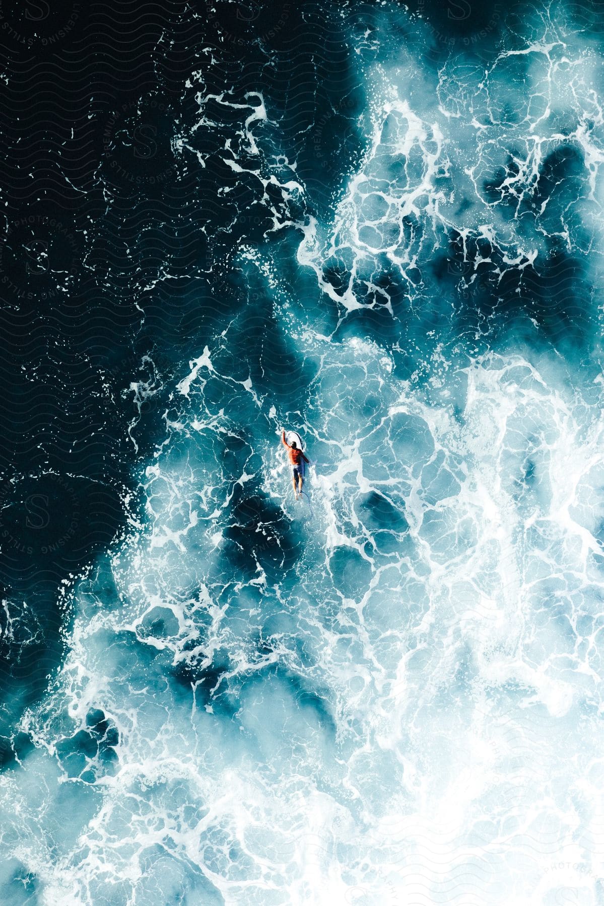 A man paddling on a surfboard from an aerial perspective