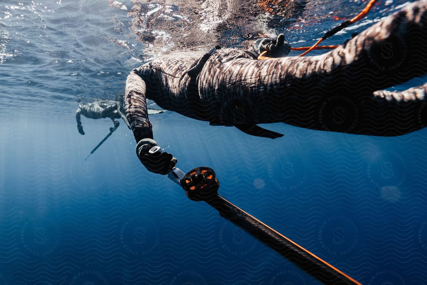 A person swimming in the sea wearing a swimsuit and holding something in their hand observed during daytime