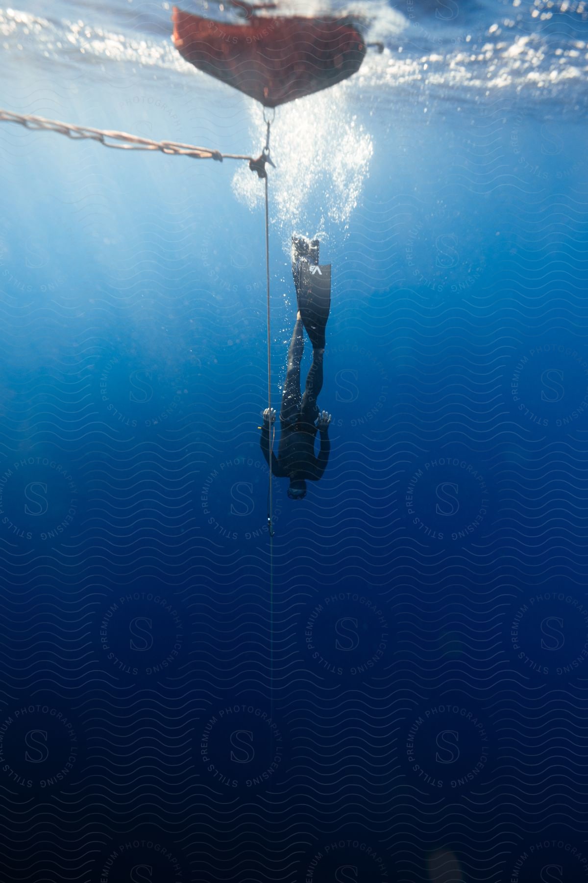 A diver swims deeper in the ocean below a marker buoy