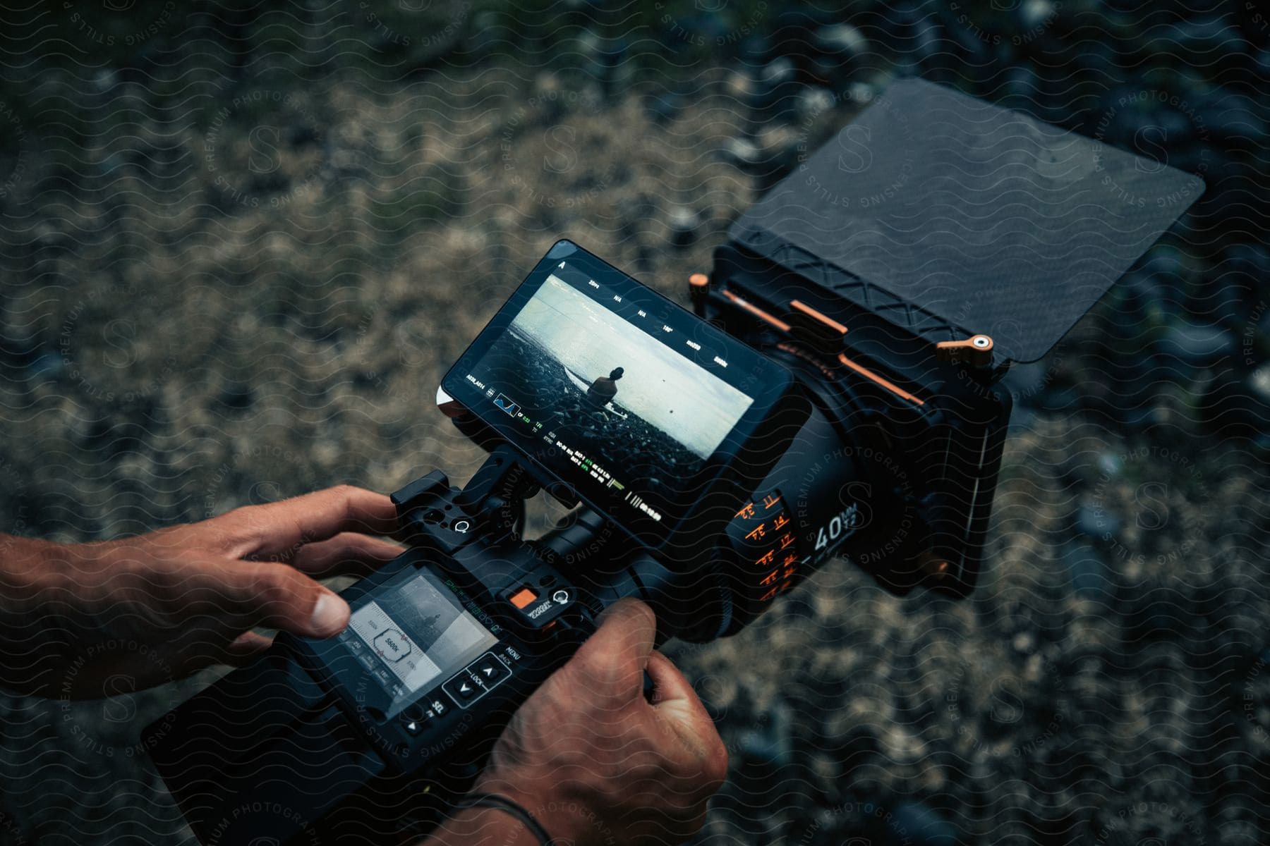 Filmmaker holding a camera with an overhead visor outdoors