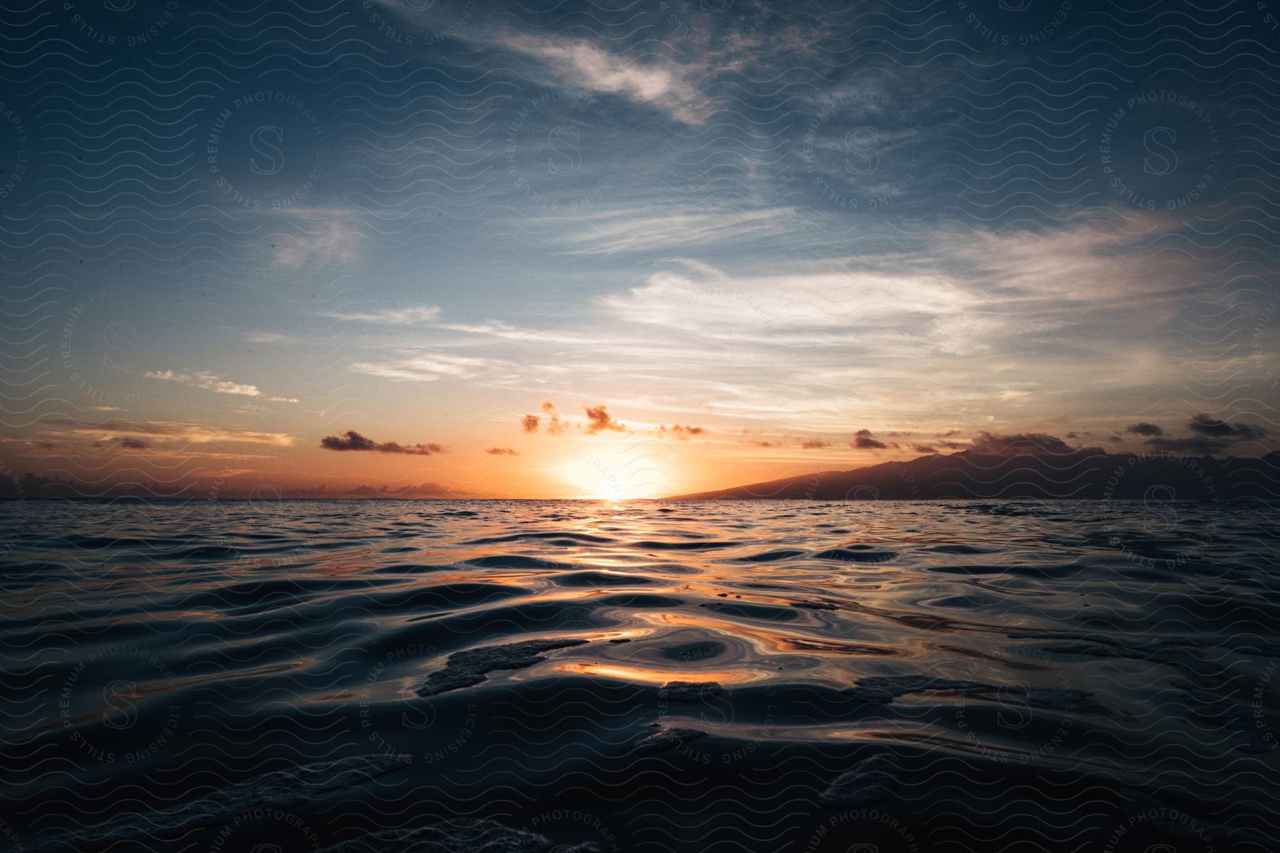 A calm ocean at sunrise with the sun rising over it