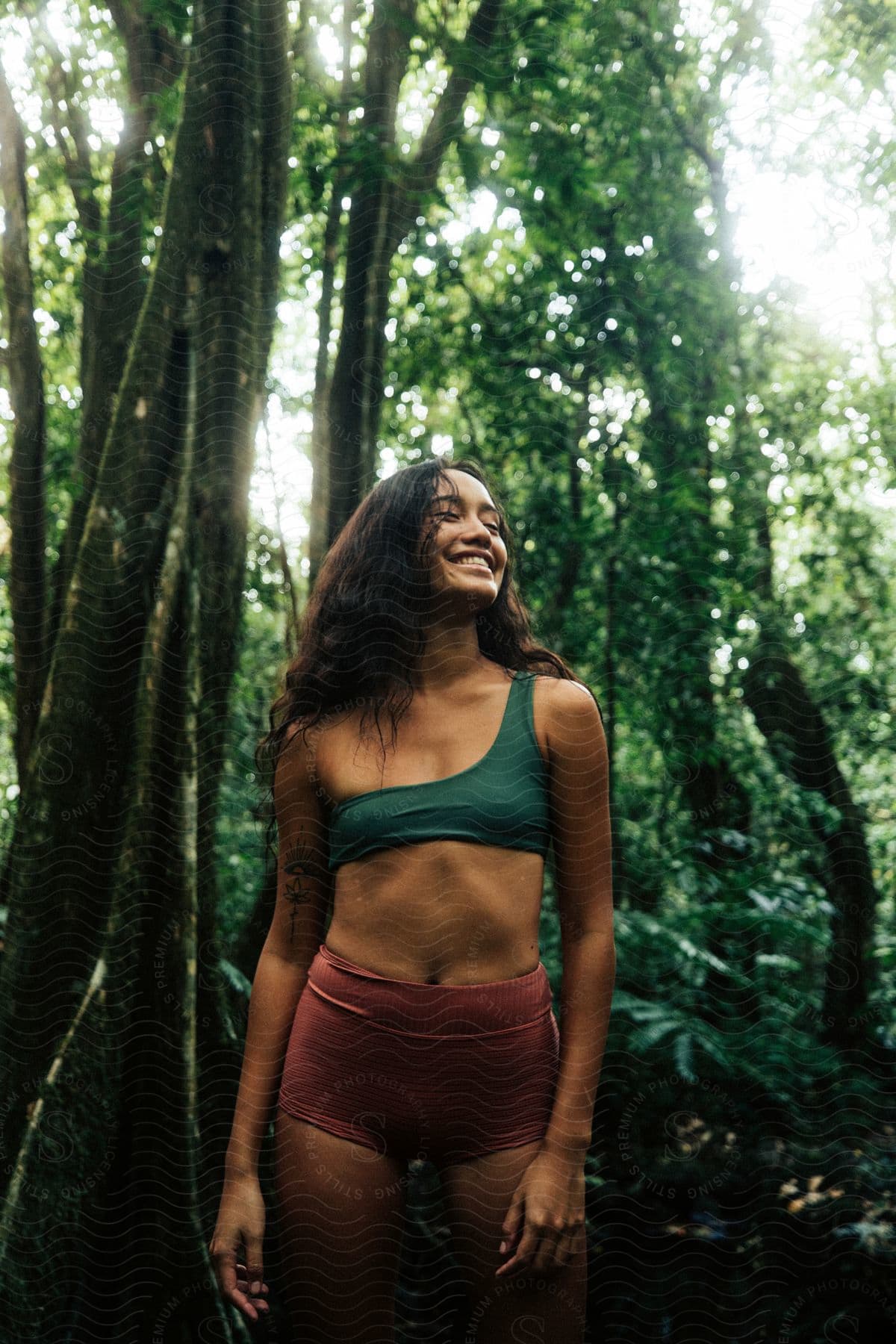 Woman smiling in rainforest with sunlight filtering through trees