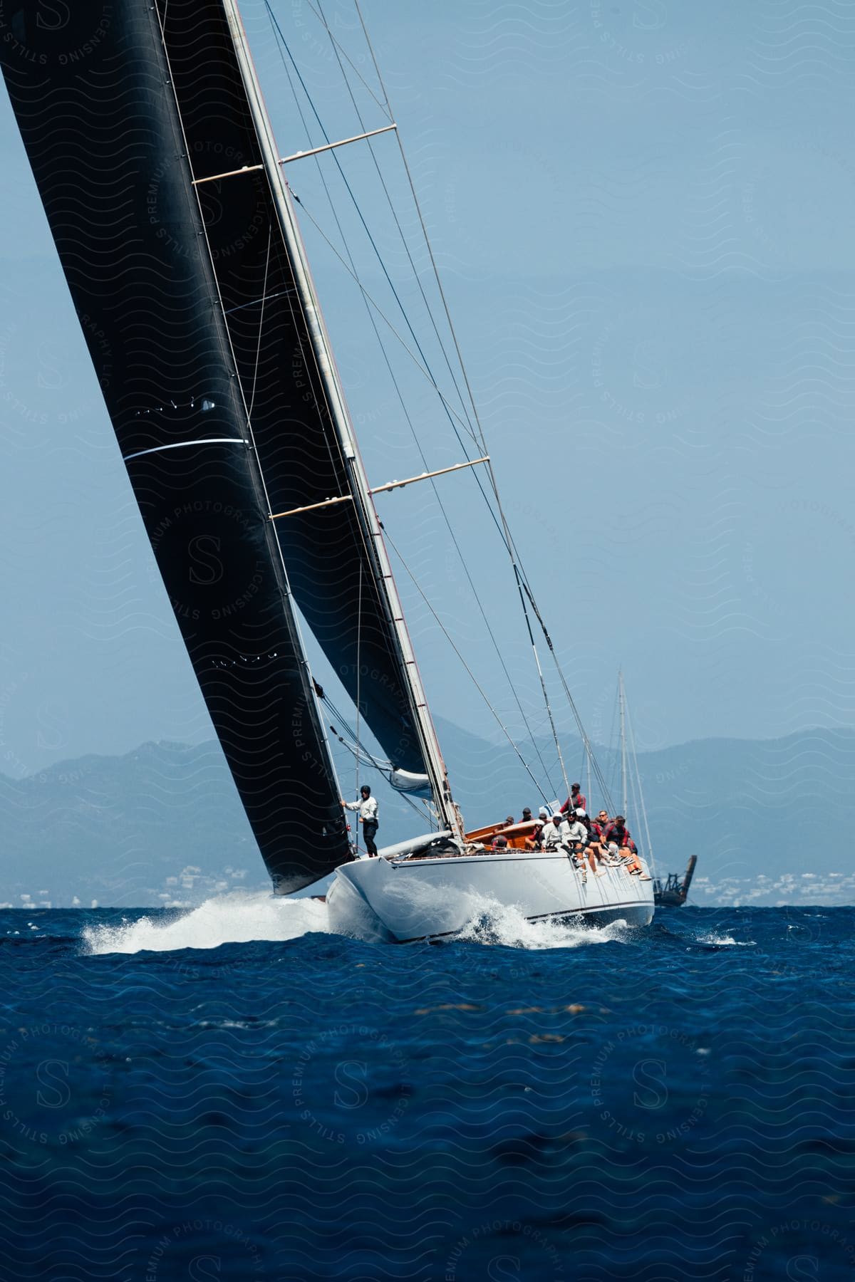 A group of people sail on a boat with many sitting over the side