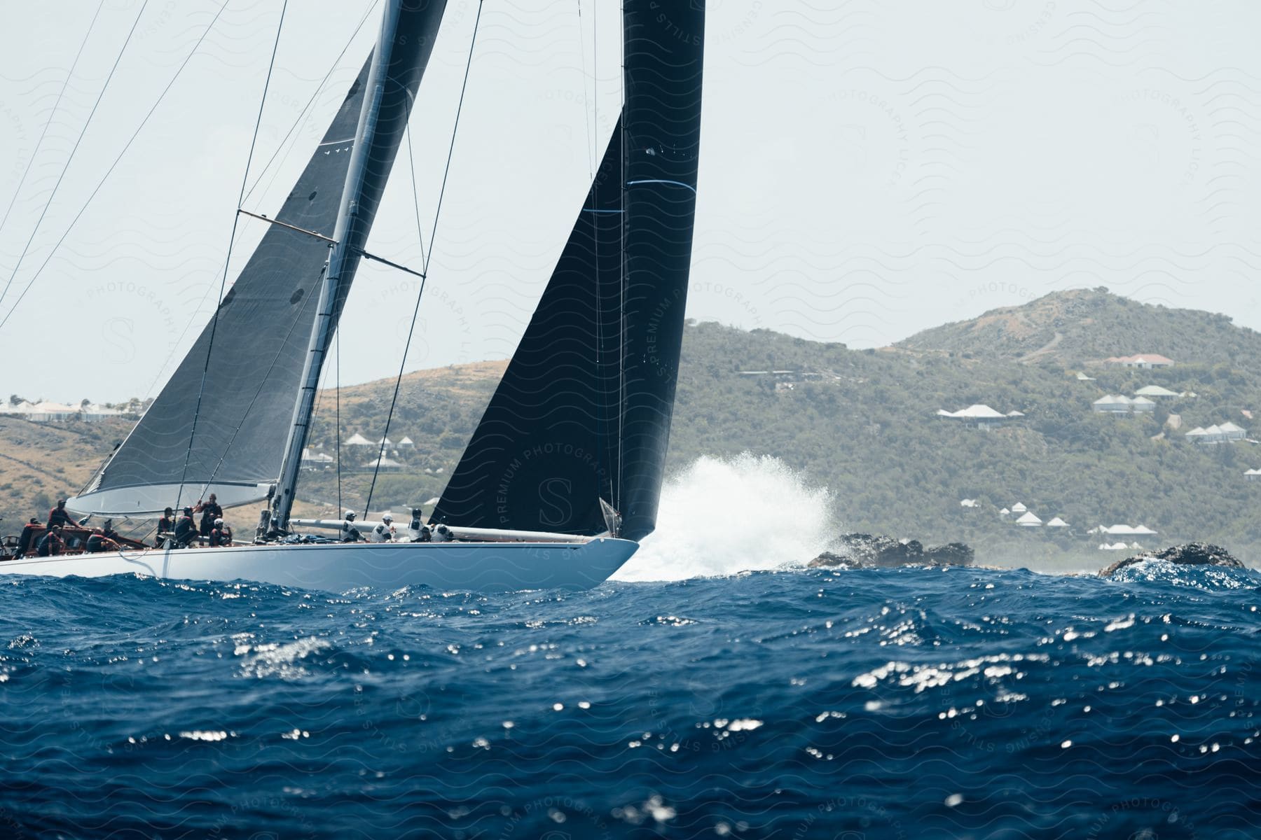 Group of people sailing on a white boat with black canvases near the coast