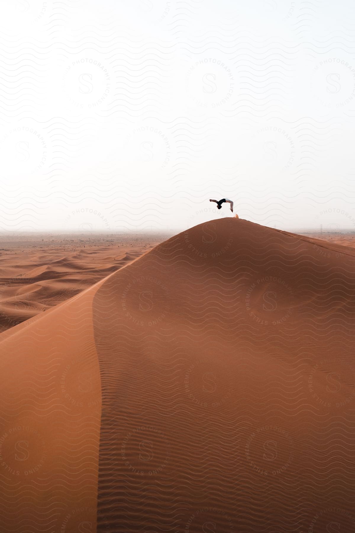 A man doing a backflip on top of a dune in saudi arabia