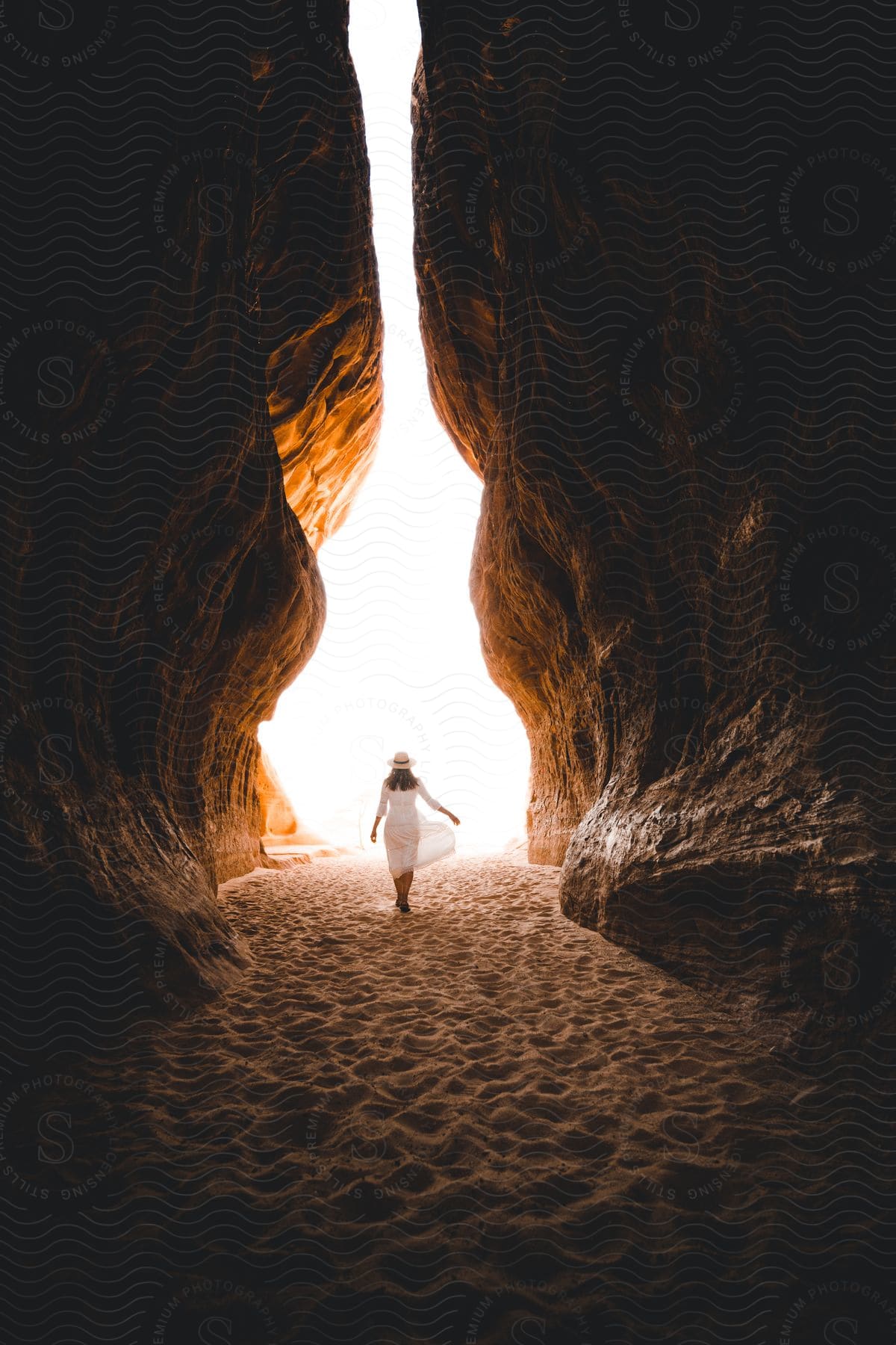 Woman walking through tunnel between cliffs towards the coast