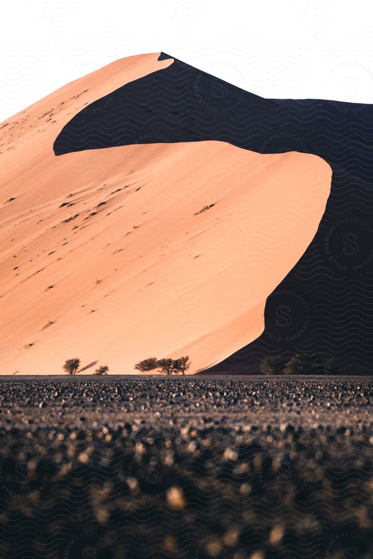 A serene desert landscape with an orange sand dune under a clear sky