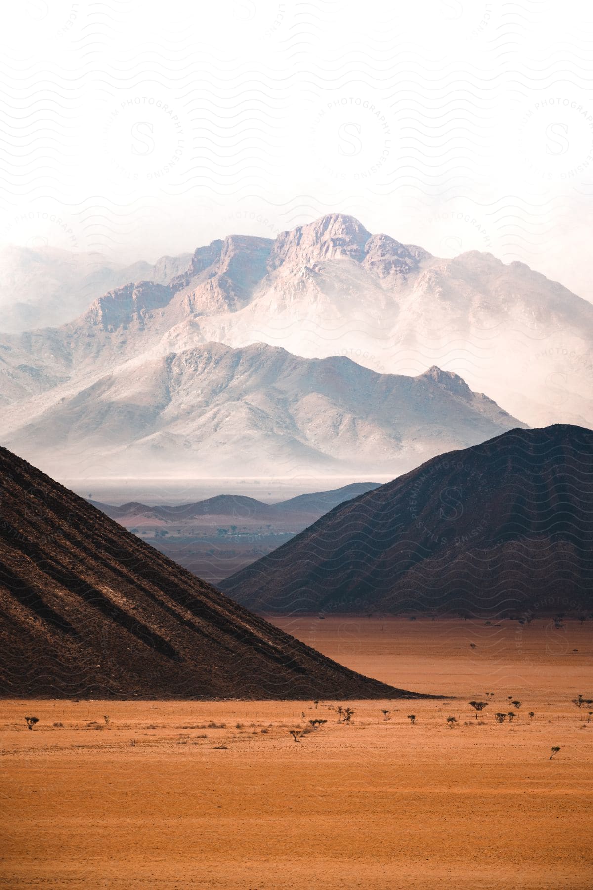 Mountains covered in clouds and mounds of dirt near orange dirt