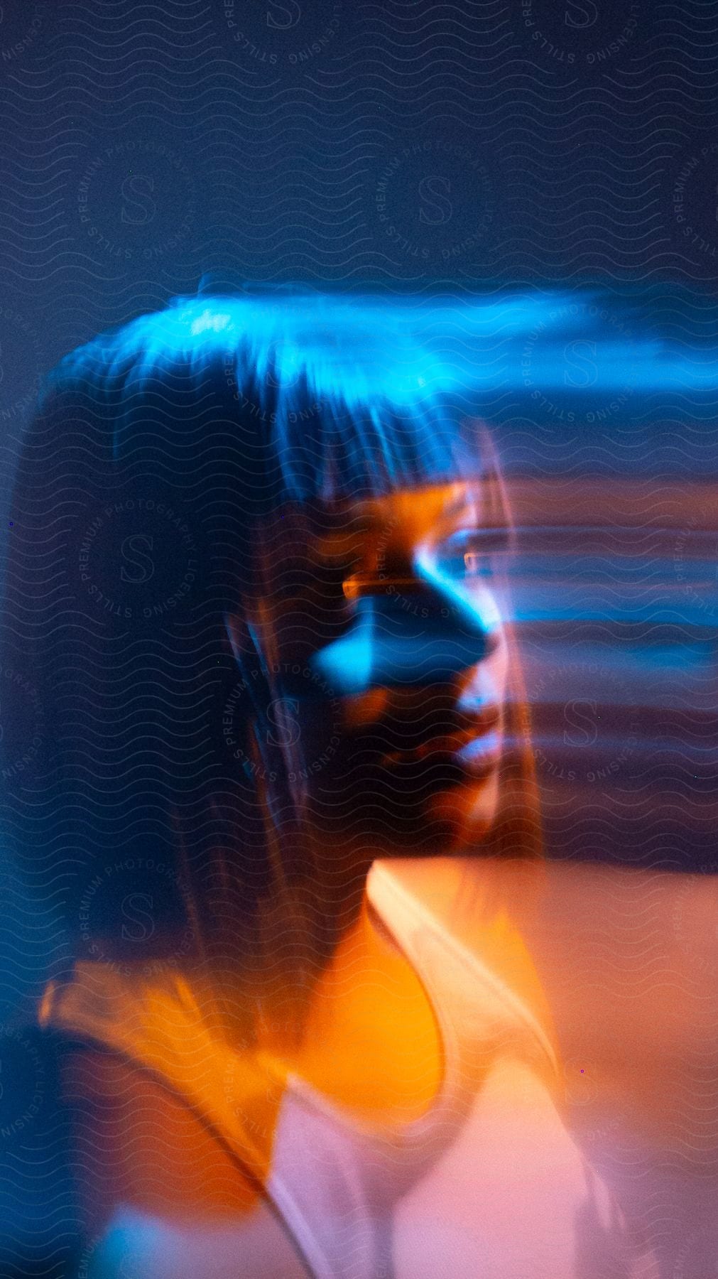 Bluehued long exposure portrait of a woman facing sideways with a trailing effect
