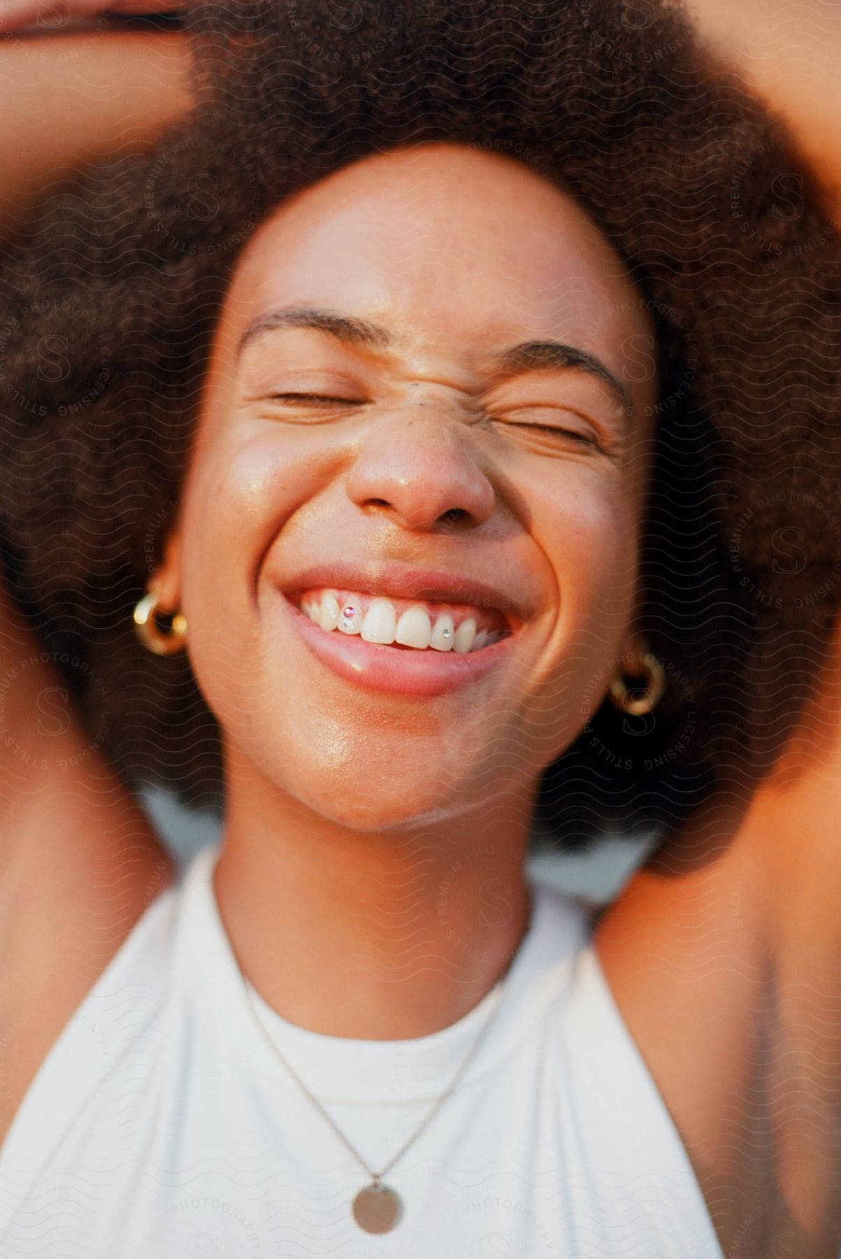 A smiling woman with jewelcovered teeth eyes closed