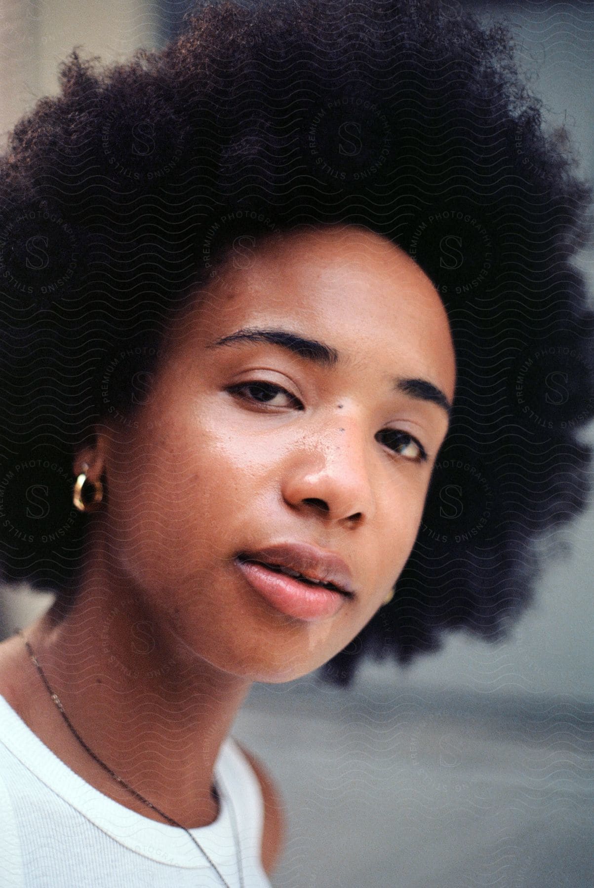 A woman in a white shirt looks at the camera