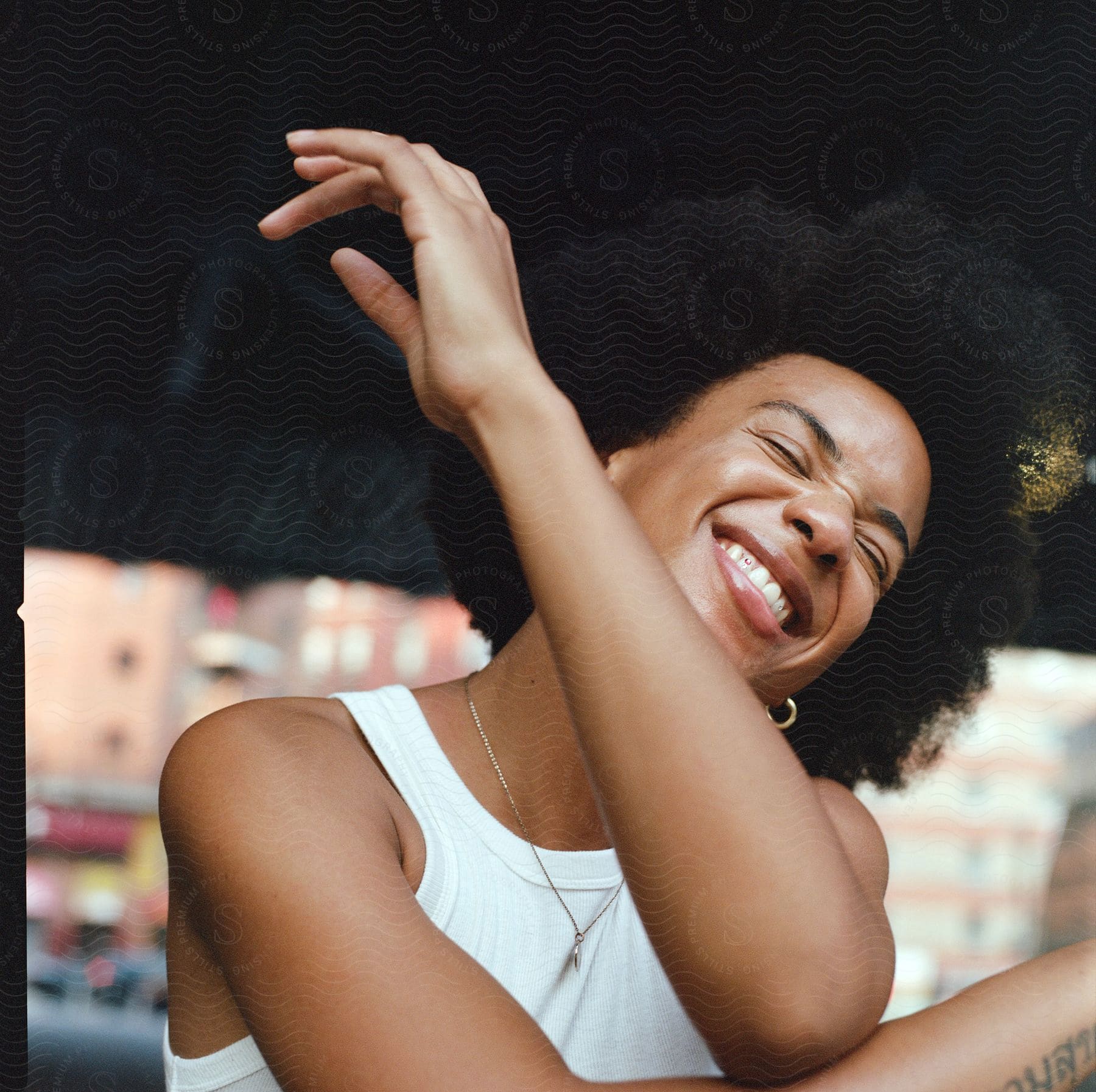 A woman with black hair smiling happily in a city setting