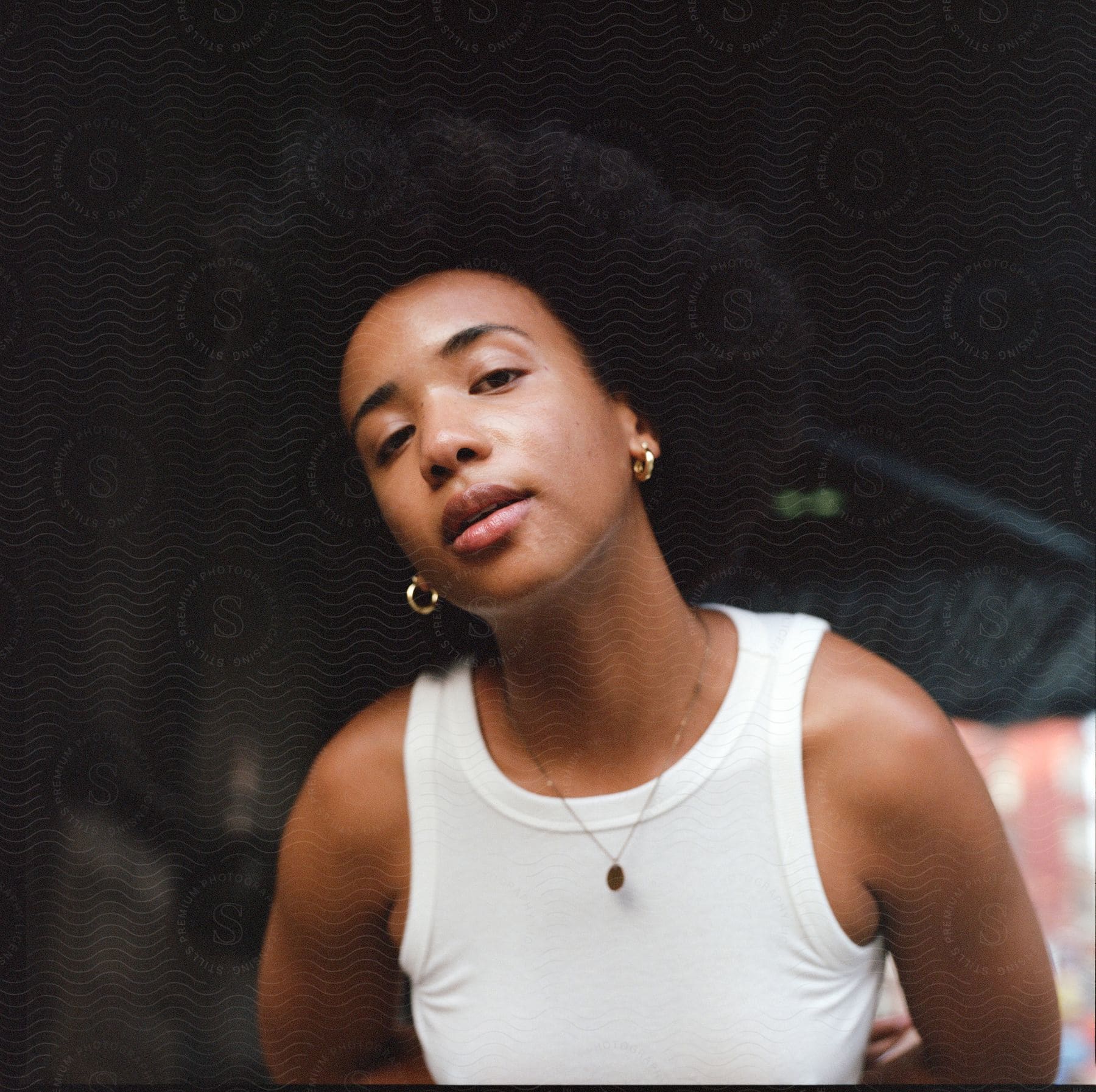 An african american woman wearing a white tank top standing outside posing