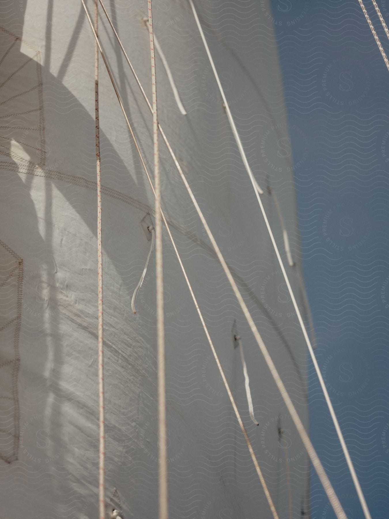 Close up of a large white sail on a boat with a blue sky