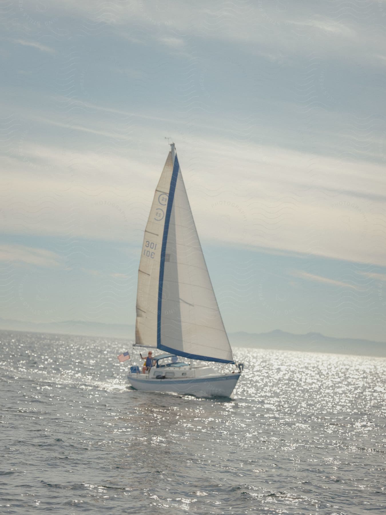 Sailboat in sunlight with man raising arm and sparkling water