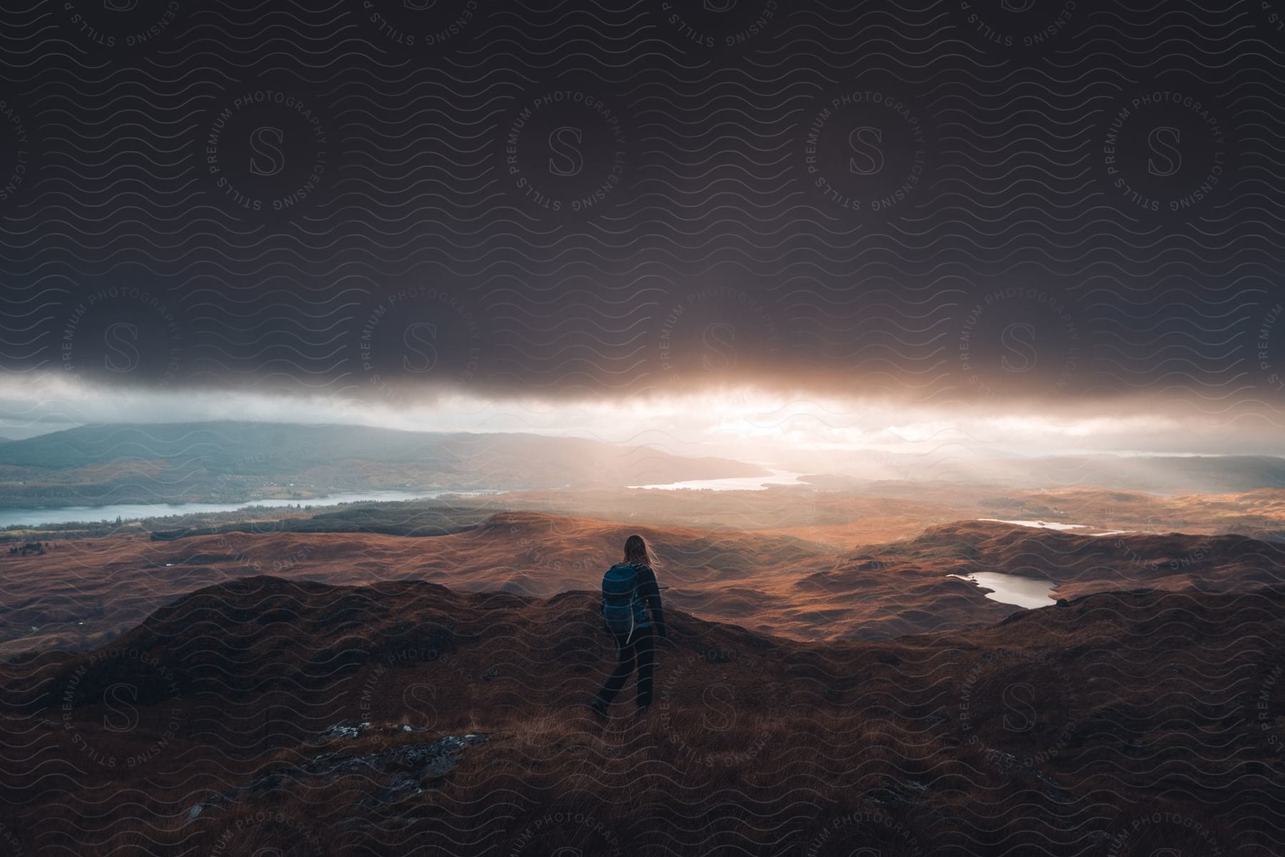 A person stands in nature with a backpack enjoying an adventure in scotland