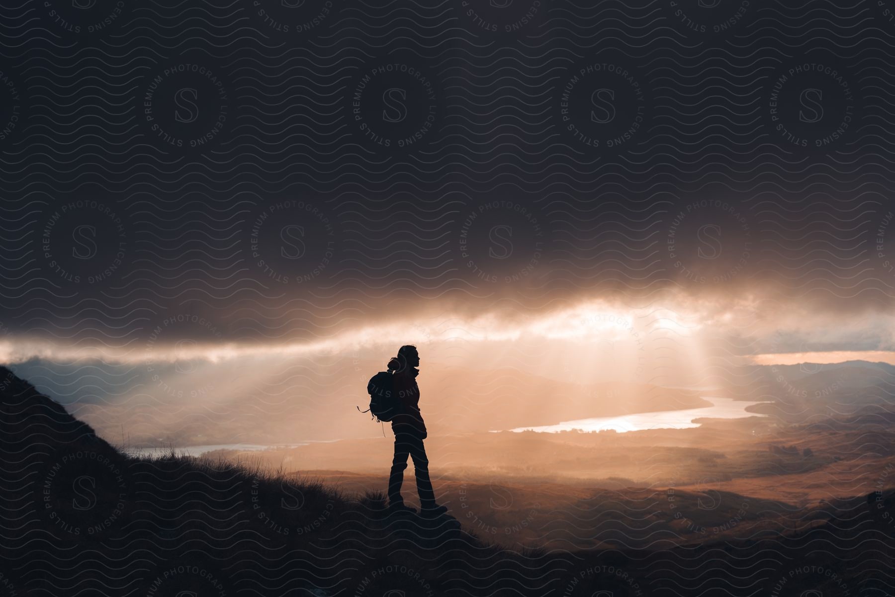 Stock photo of a person hiking in the wilderness at dusk or dawn with a backpack